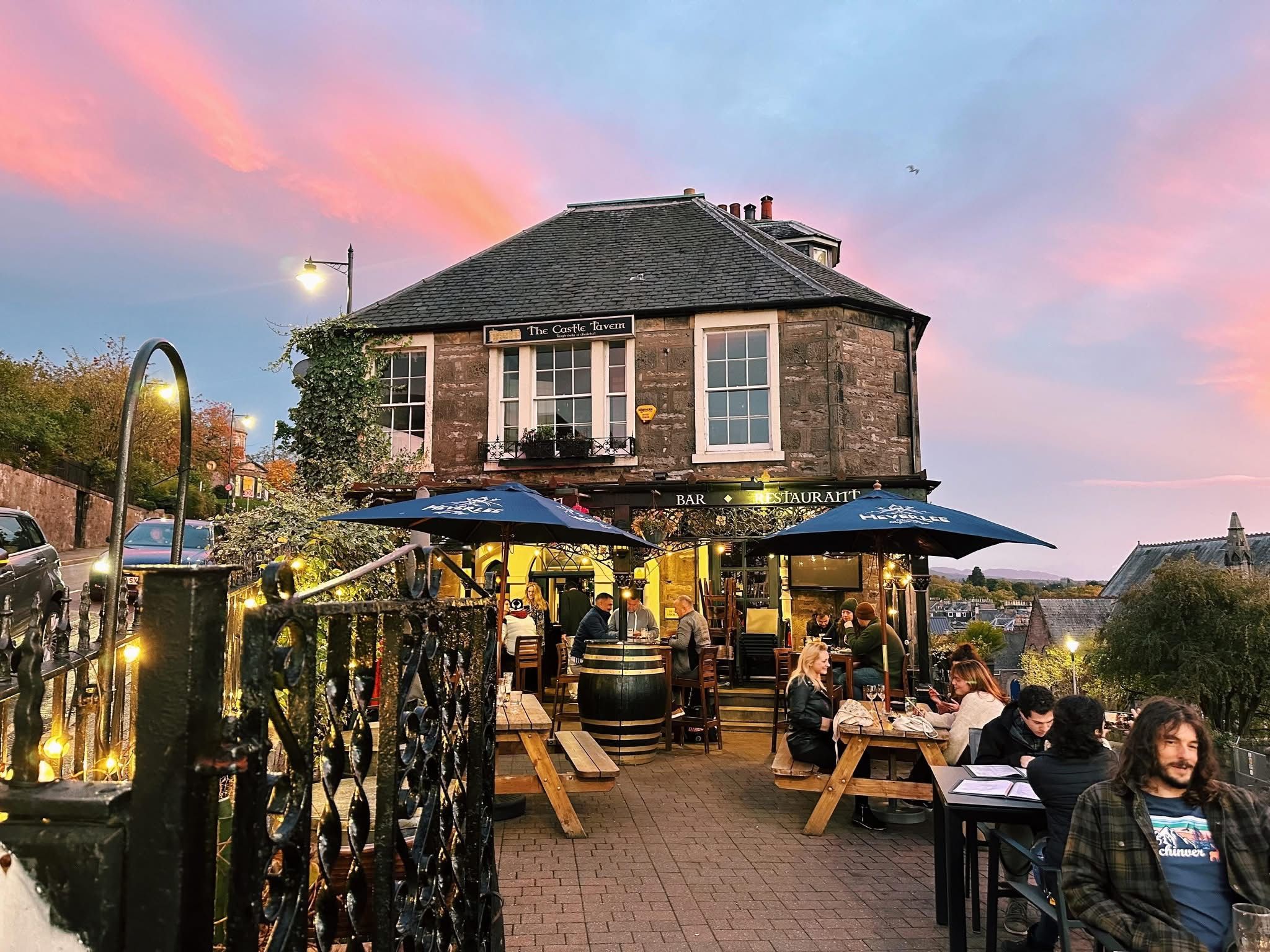 The Castle Tavern outdoor seating at sunset with string lights