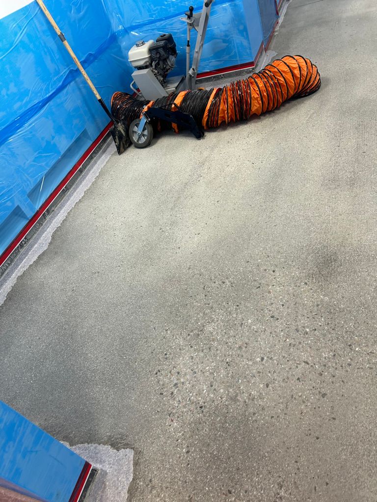 Surface preparation in progress on a pharmaceutical floor — floor grinding equipment and ventilation hose on bare concrete slab