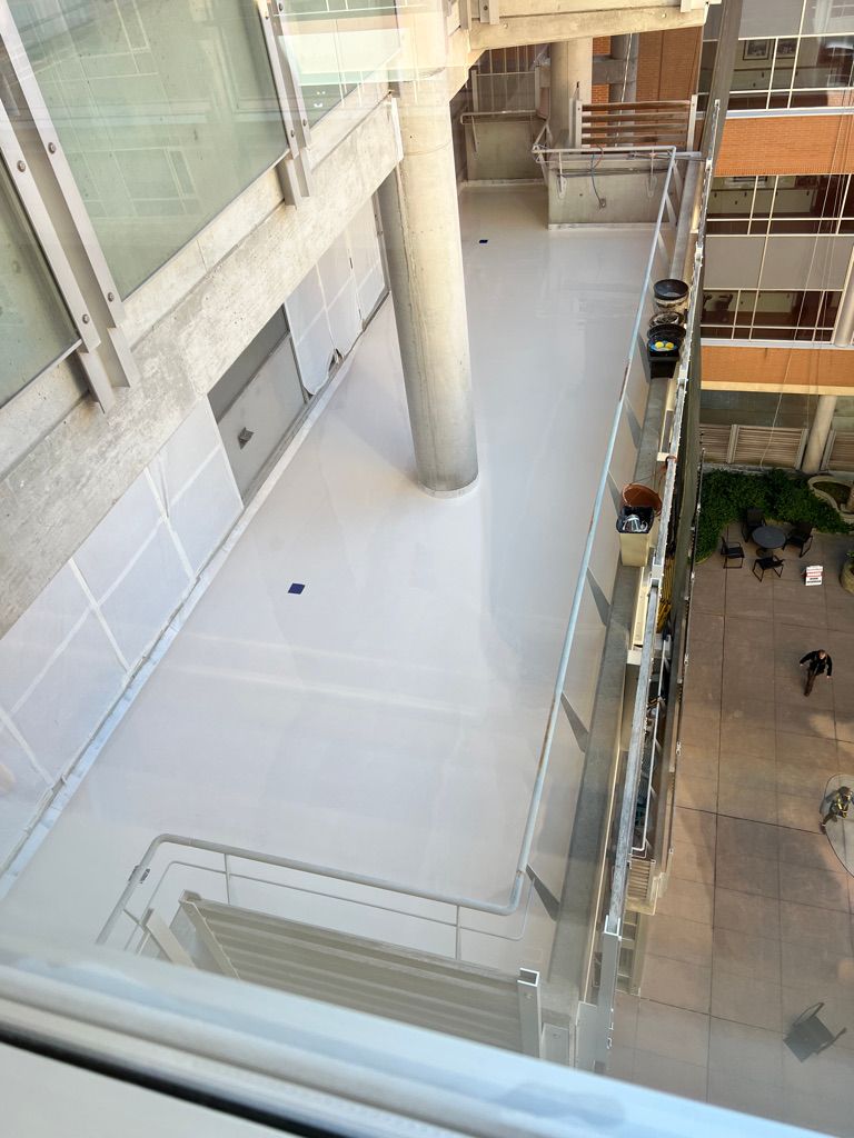 High-angle view of modern healthcare facility with white glossy seamless floor, concrete pillar, glass railings and outdoor patio area