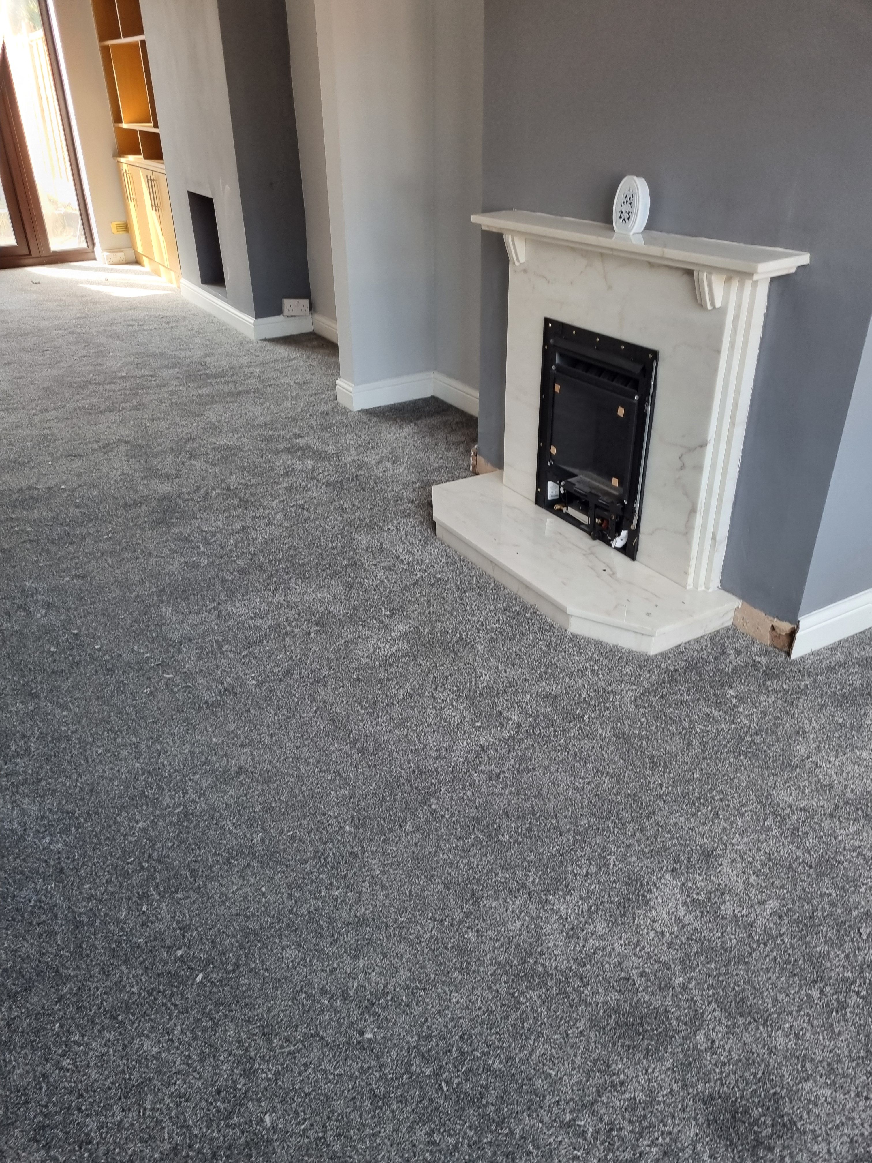 Living room carpet installation with fireplace