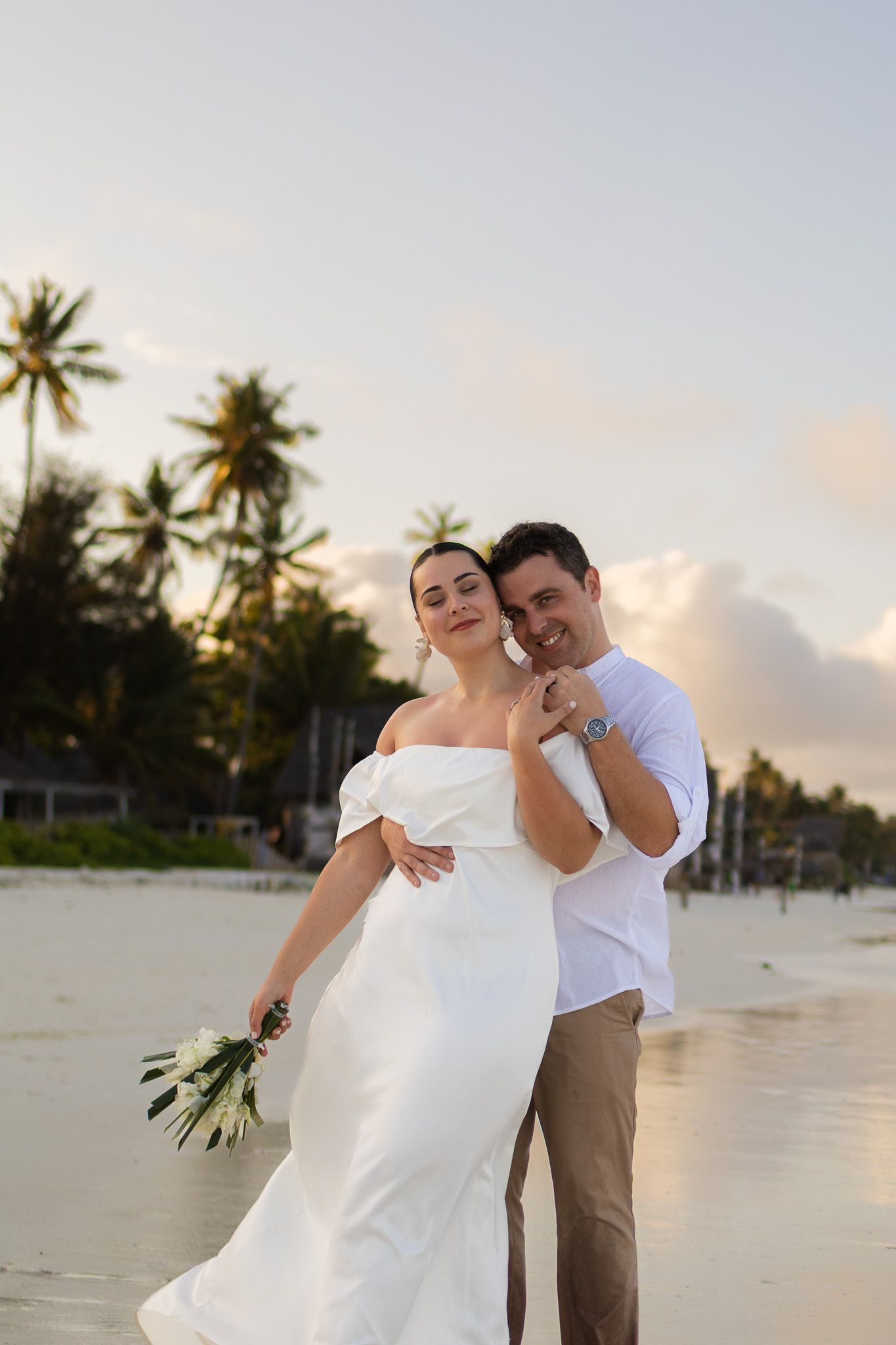 Couple on beach at sunset with white bouquet