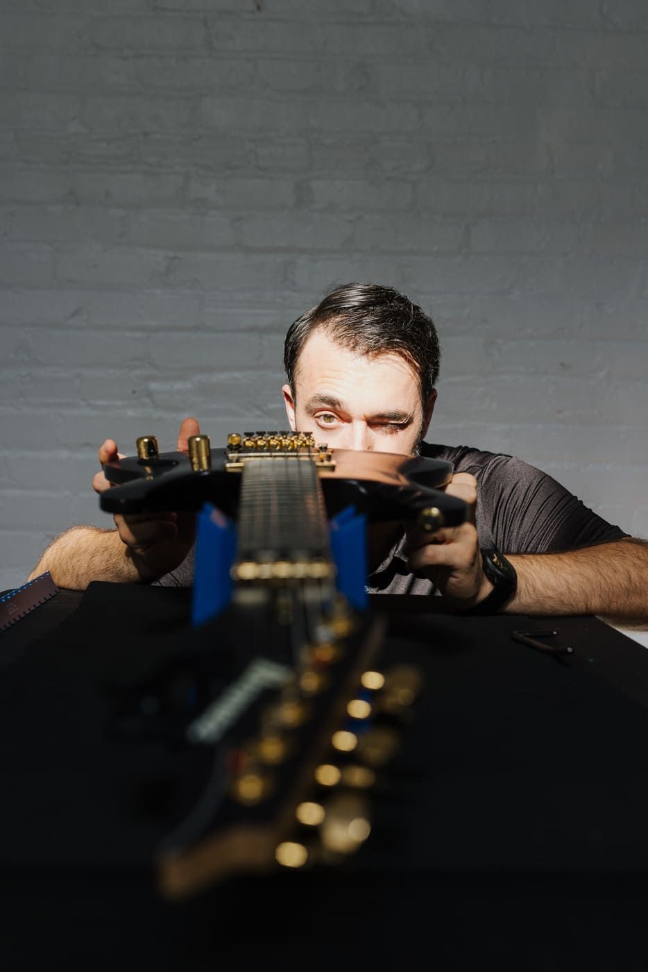 Tyler sighting down the neck of a guitar to inspect its condition — professional judgment and expertise