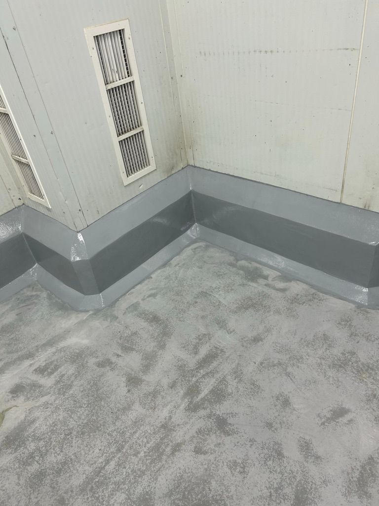 Completed food facility room with restored smooth gray floor and cove base, white walls and ventilation grilles