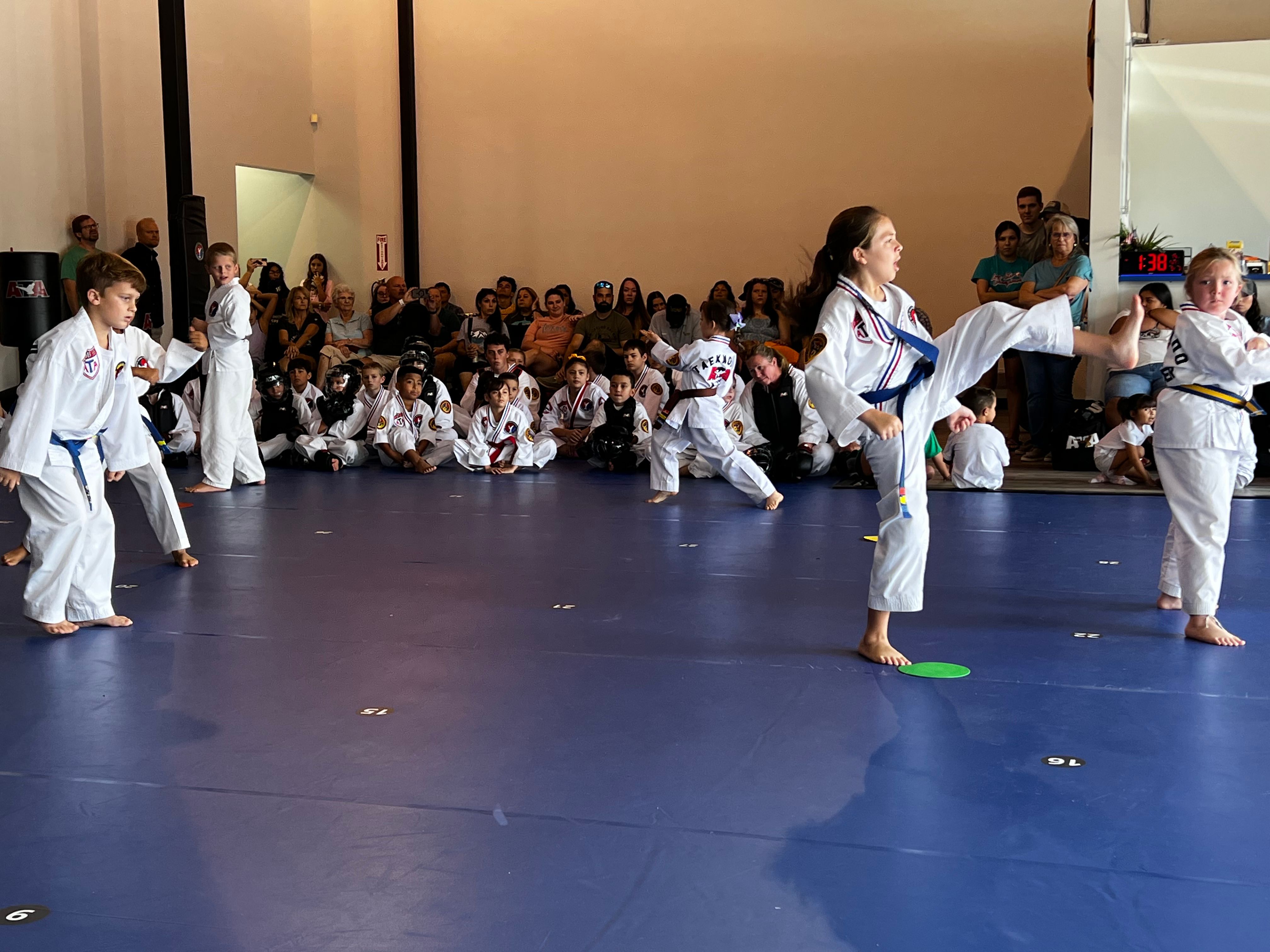 Junior Taekwondo students practicing kicks on the mat