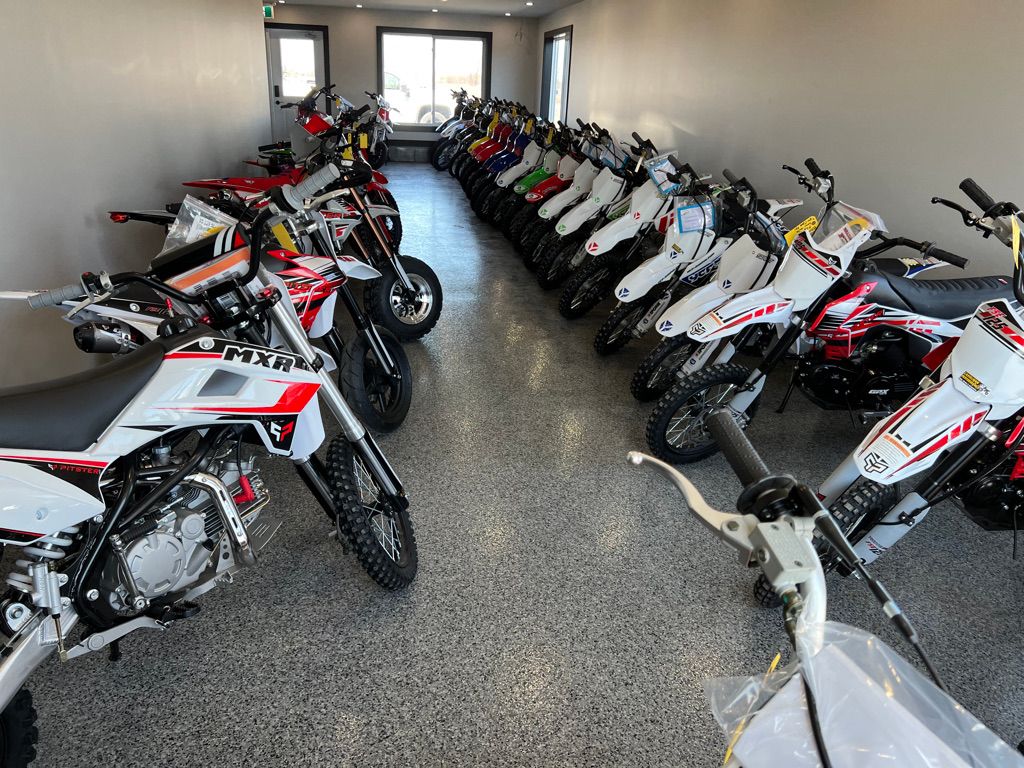 Polished reflective showroom floor with two rows of white MXR motorcycles facing each other under bright even lighting