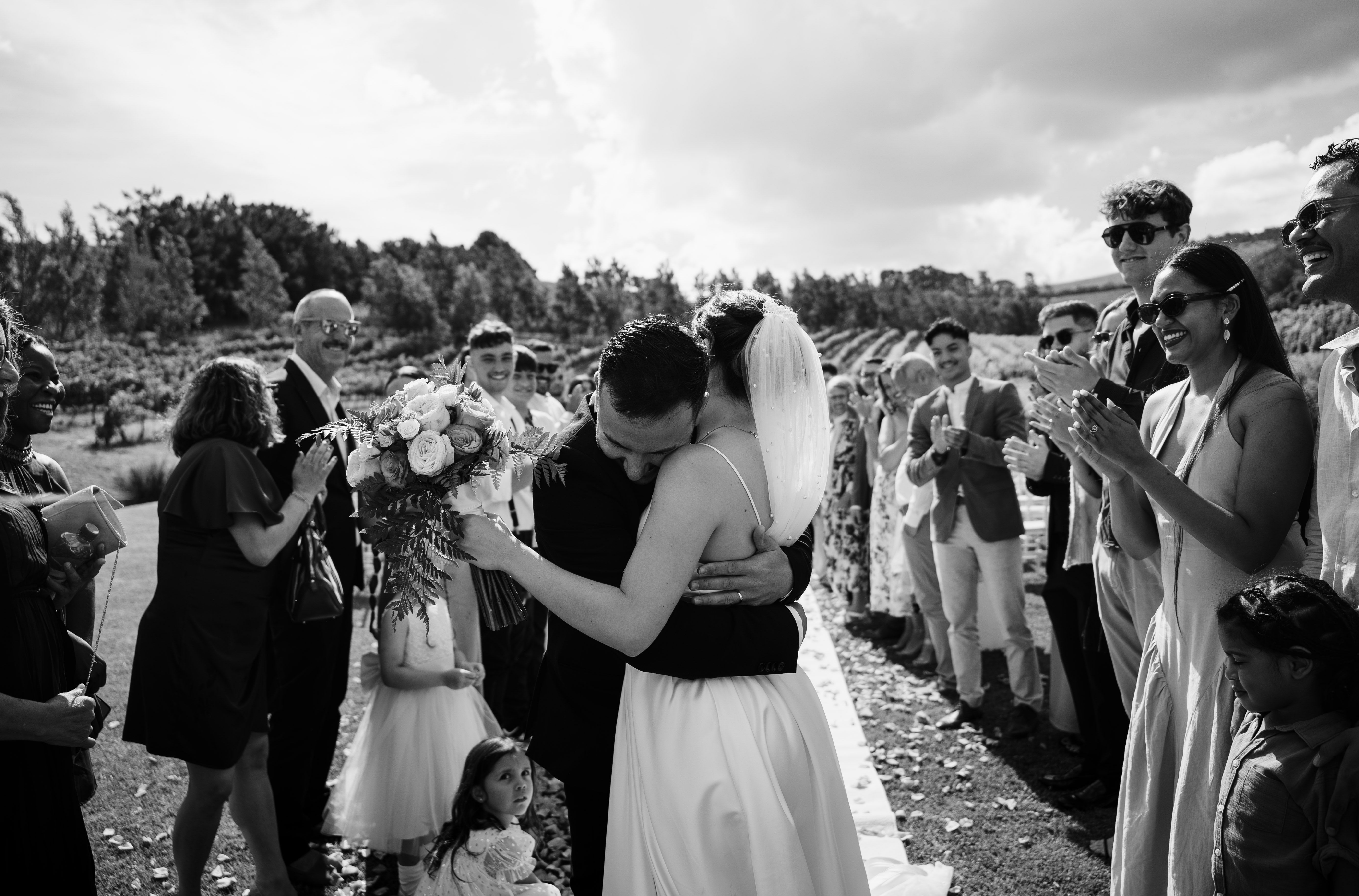 Wedding couple embracing while guests celebrate