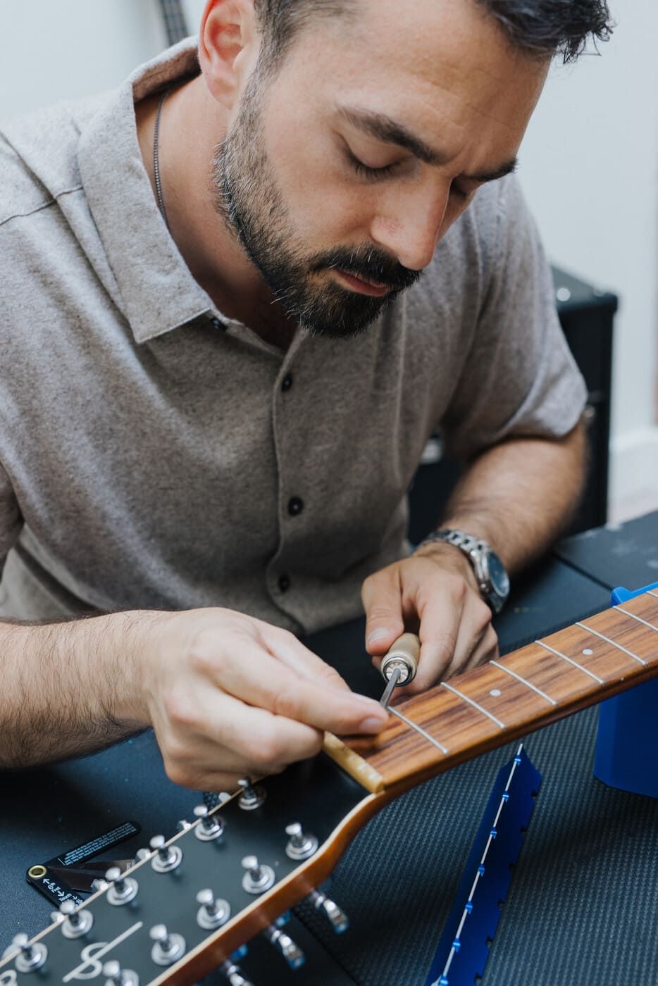 Tyler carefully adjusting guitar frets with a screwdriver