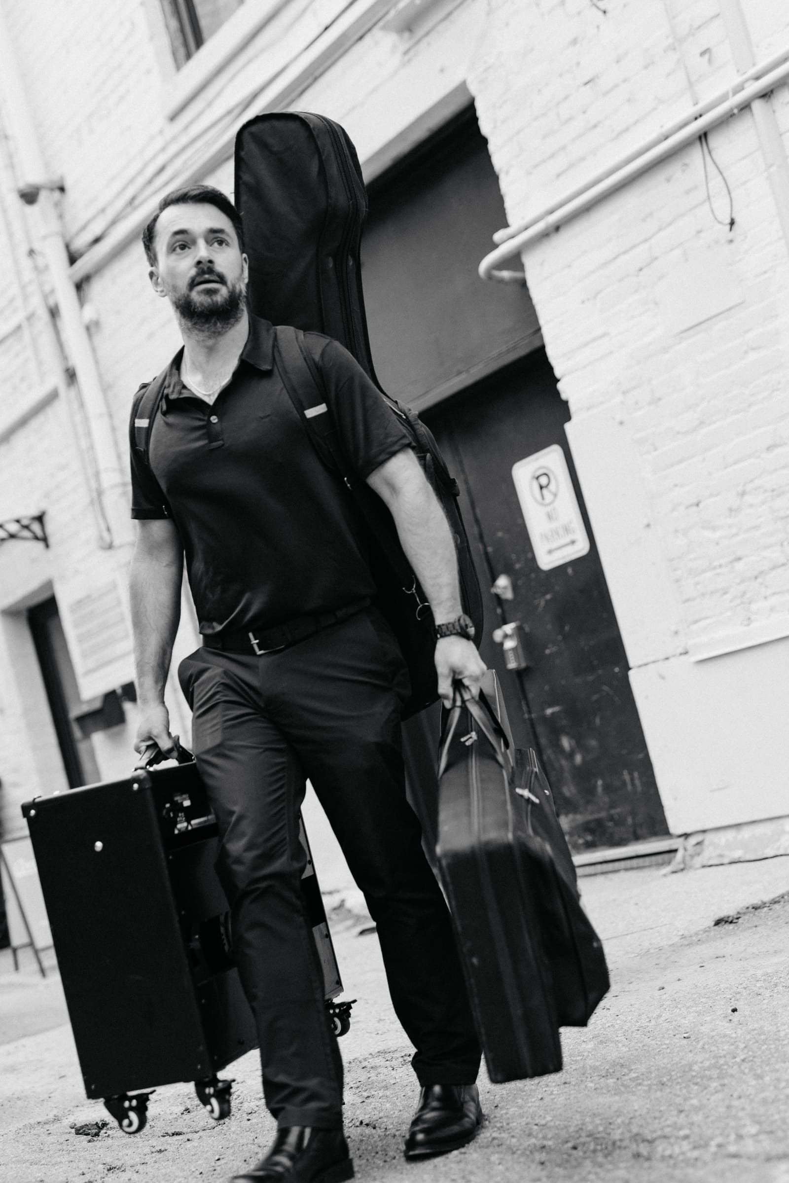 Tyler walking outdoors carrying guitar cases - mobile guitar technician on the go