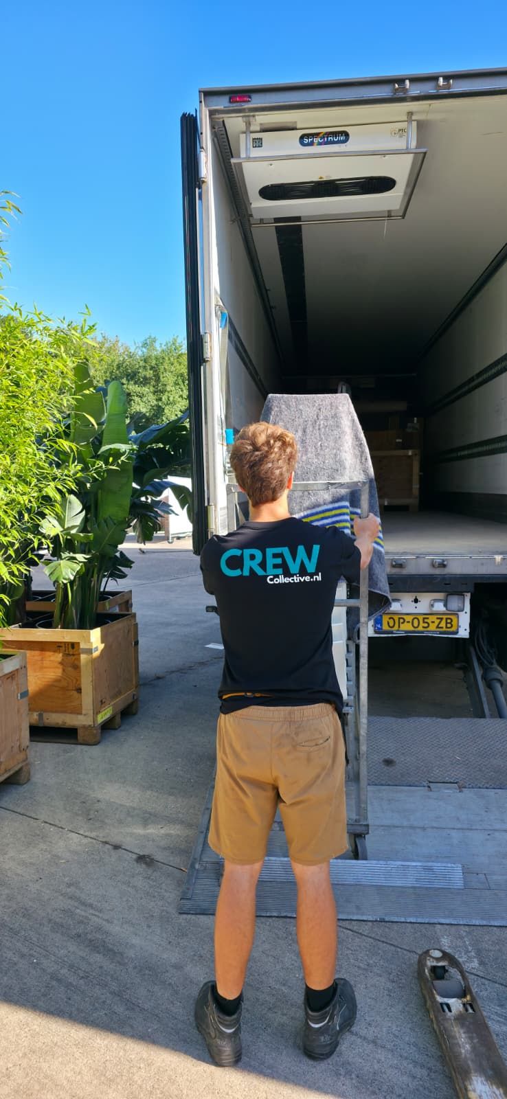 Crewleden laden dozen en eventmateriaal in een vrachtwagen op een laadperron