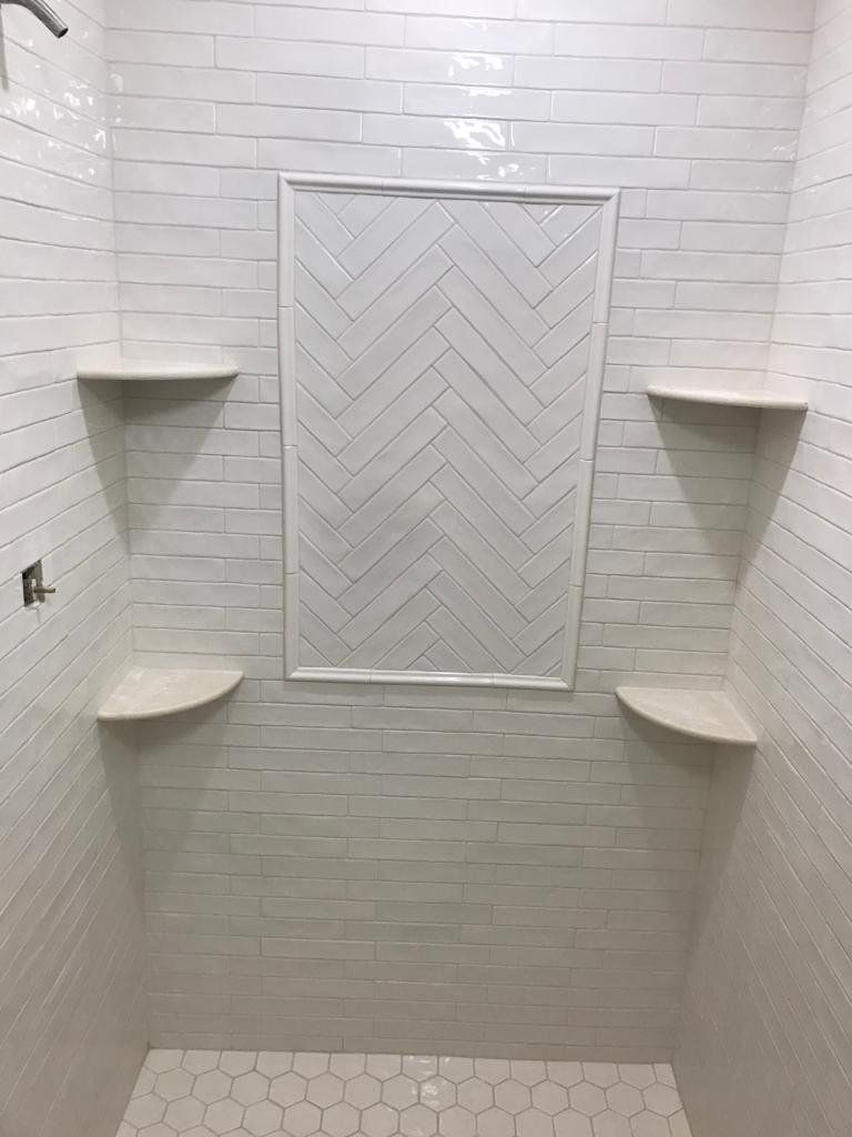 Shower with herringbone accent niche and corner shelves