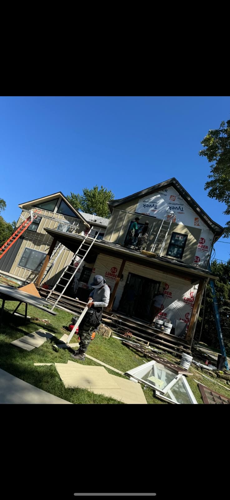 House under construction with workers installing siding and exterior materials