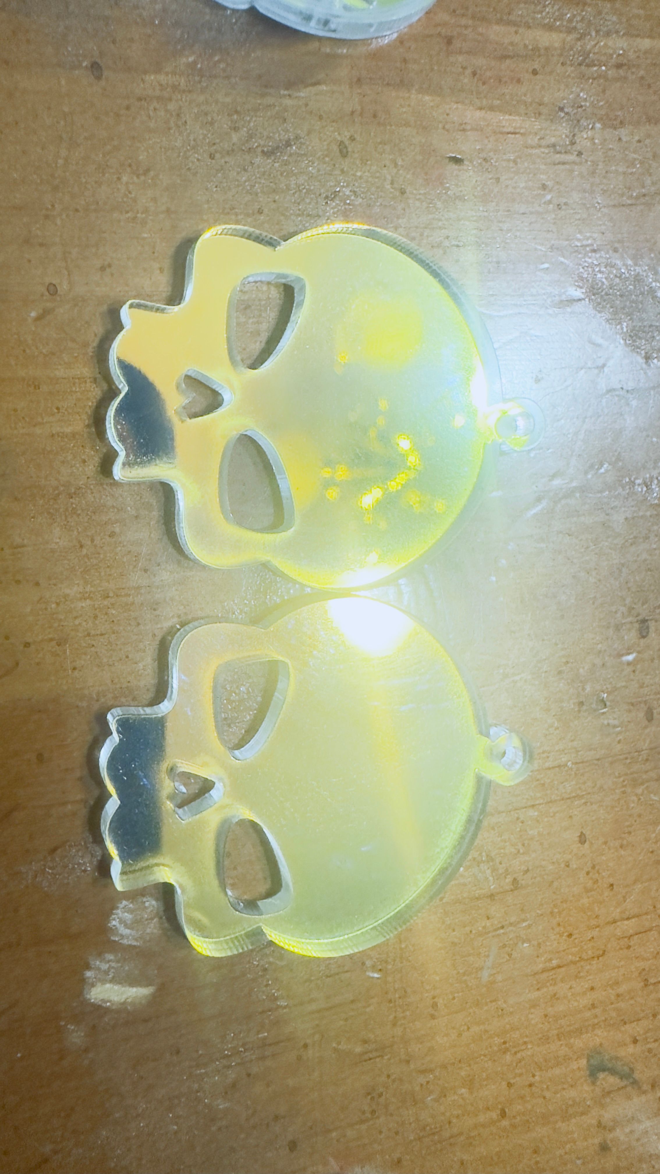Two translucent skull-shaped acrylic keychains on a wooden surface