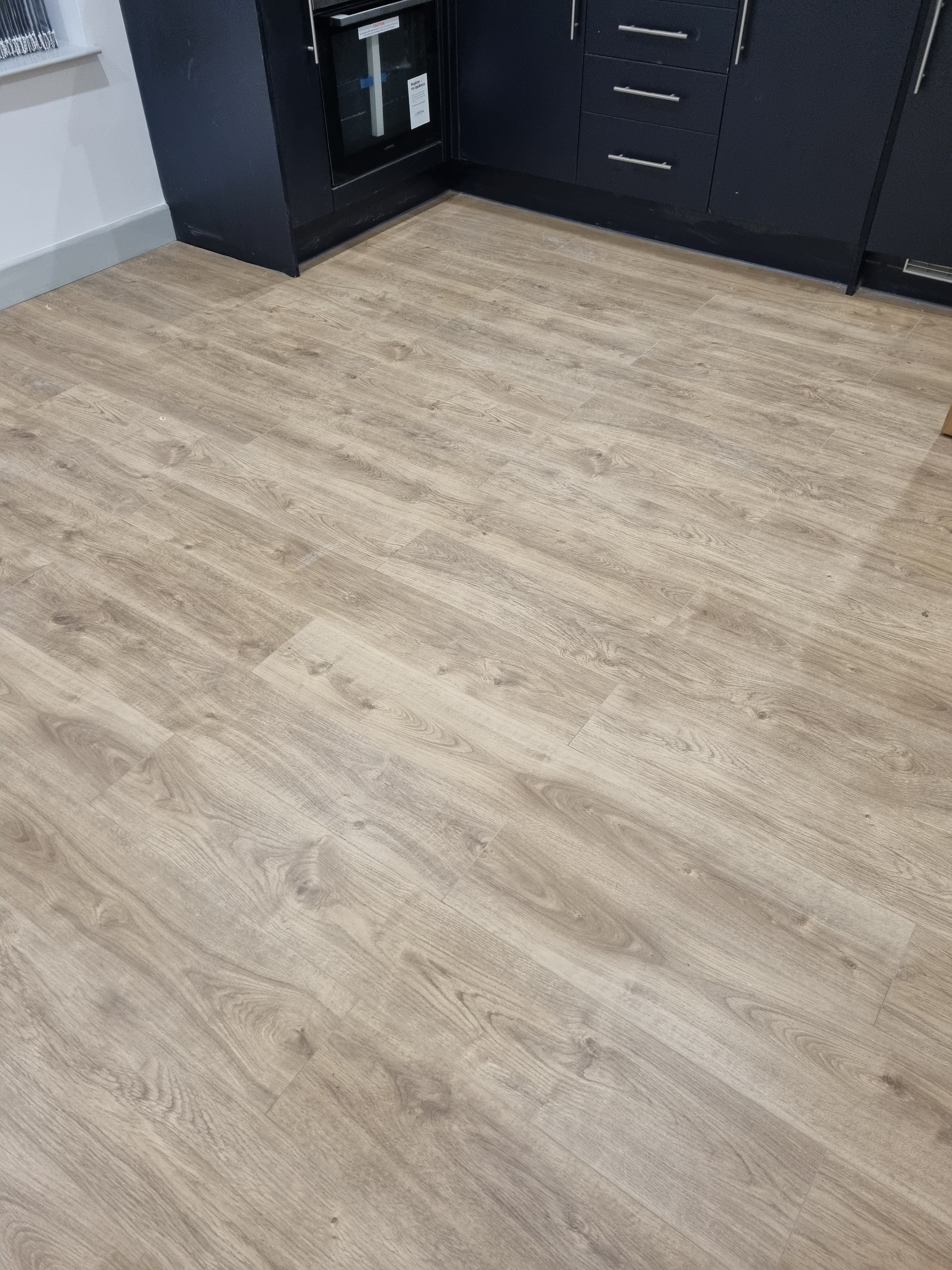 Kitchen with light brown laminate wood flooring and black cabinets
