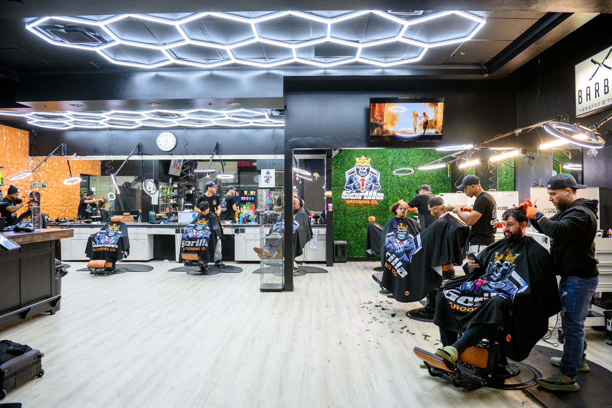Gorilla Grooming Co. shop interior — neon sign, green wall, barbers at work