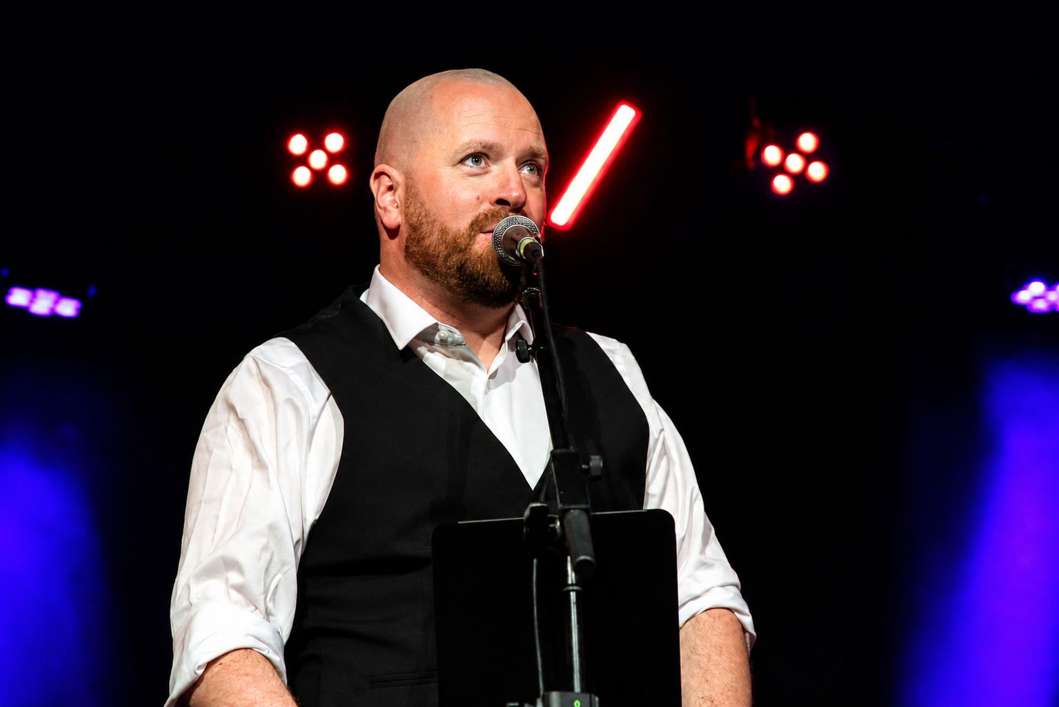 Ryan Wallace — The Opera Guy performing on stage with dramatic red and purple lighting
