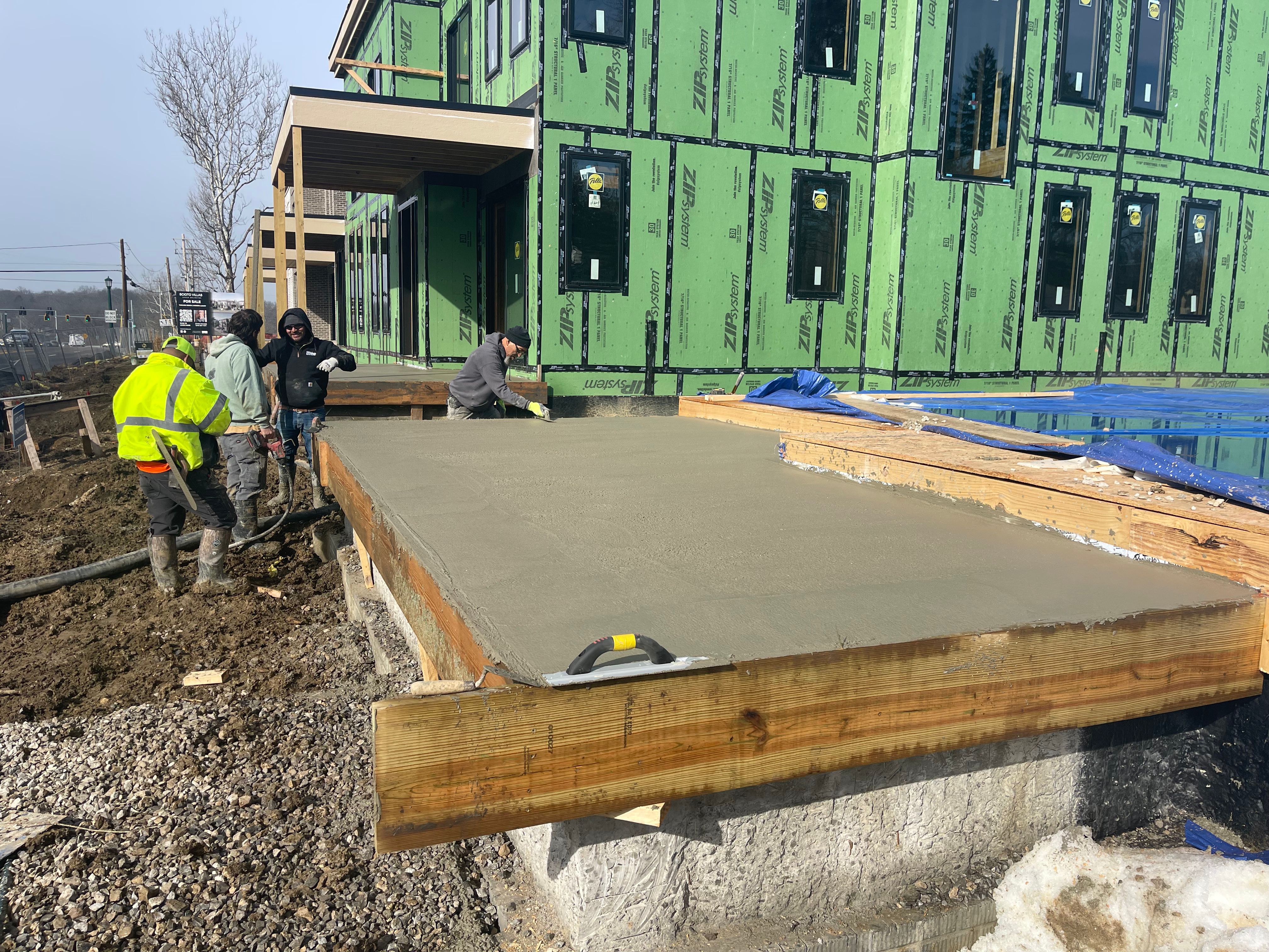 Crew finishing concrete slab next to building under construction in Columbus Ohio
