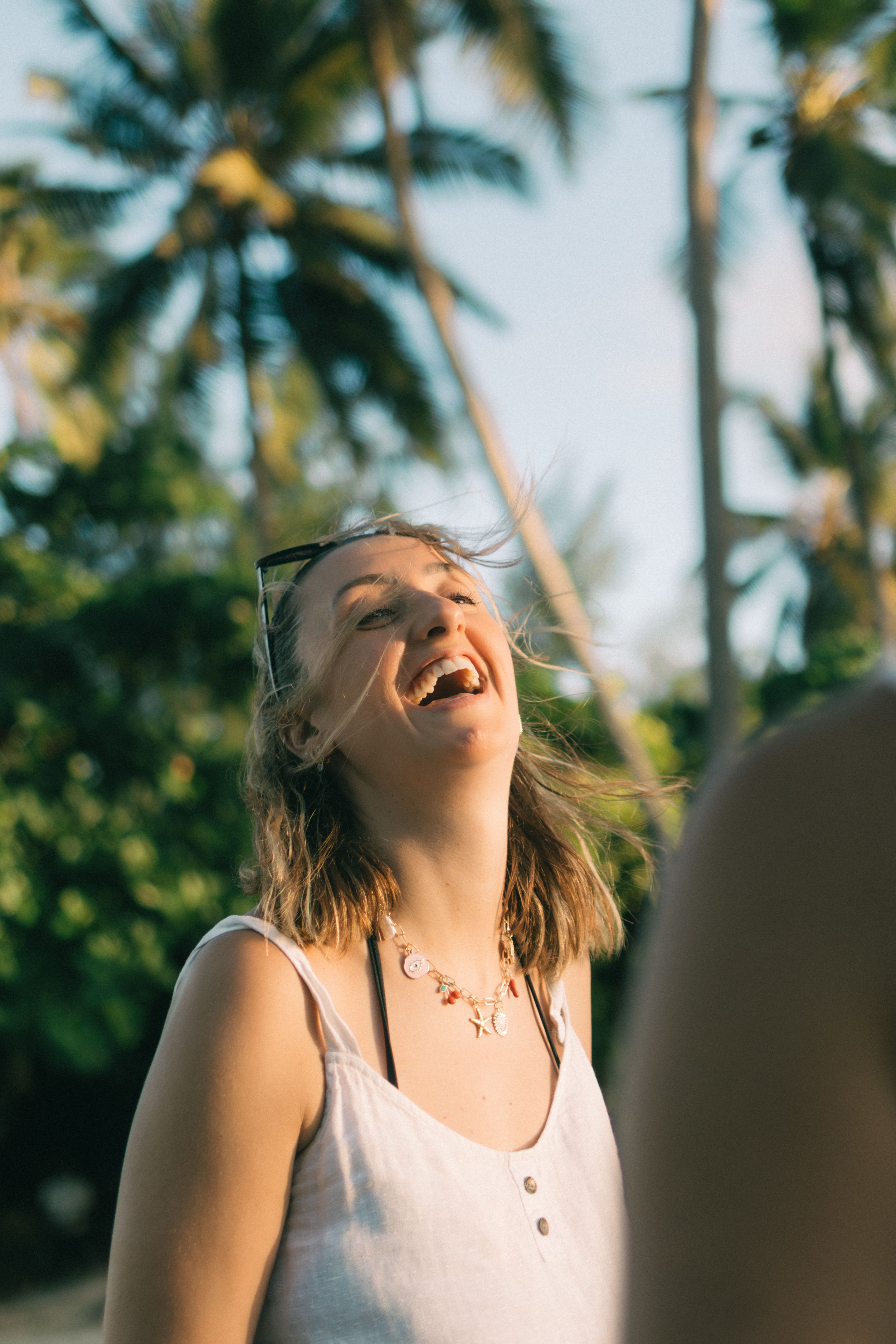 Kate laughing under palm trees in Zanzibar
