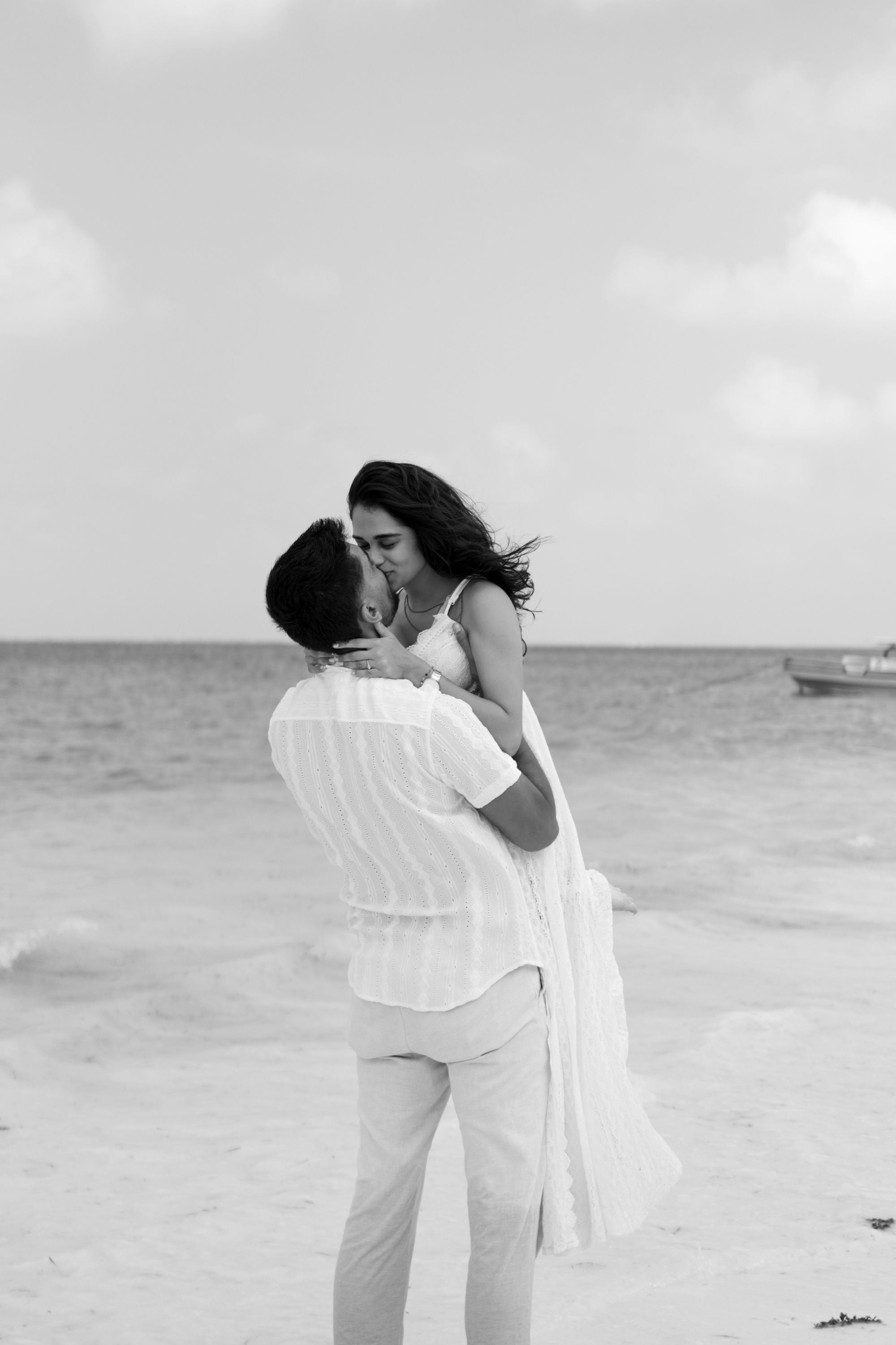 Black and white photo of couple lifted kiss on beach