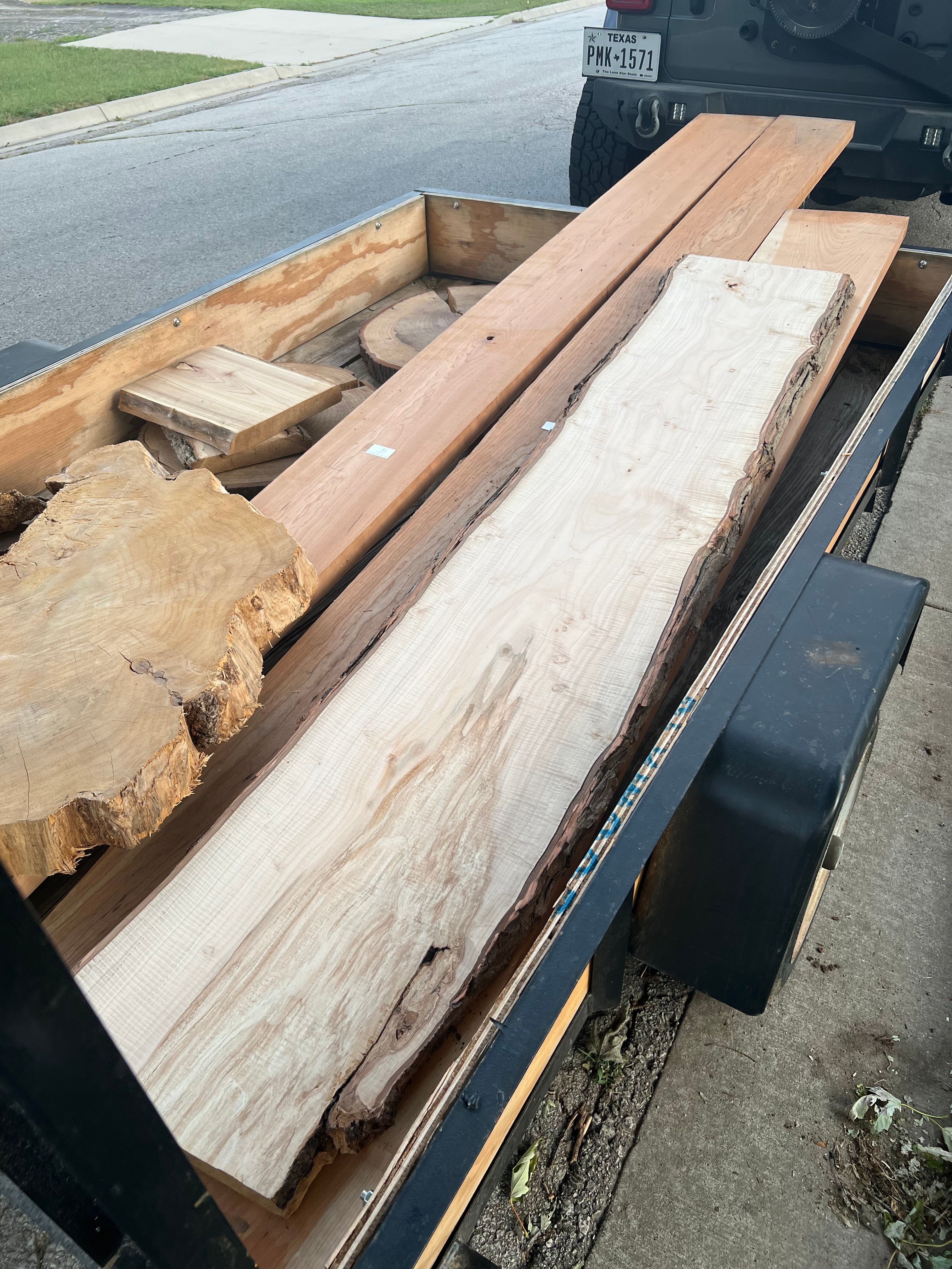 Trailer loaded with various wood pieces including live edge slabs