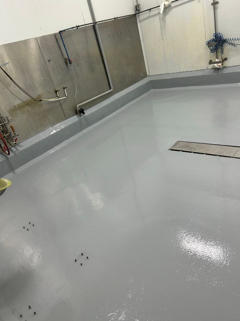 Completed commercial room with glossy gray floor, recessed floor grate and wall-mounted coiled hose rack