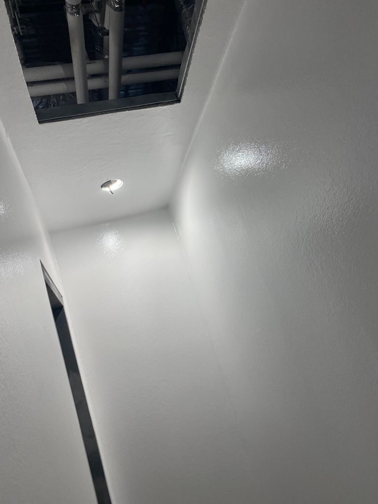 Manufacturing facility room with seamless white epoxy walls and ceiling showing plumbing rough-in