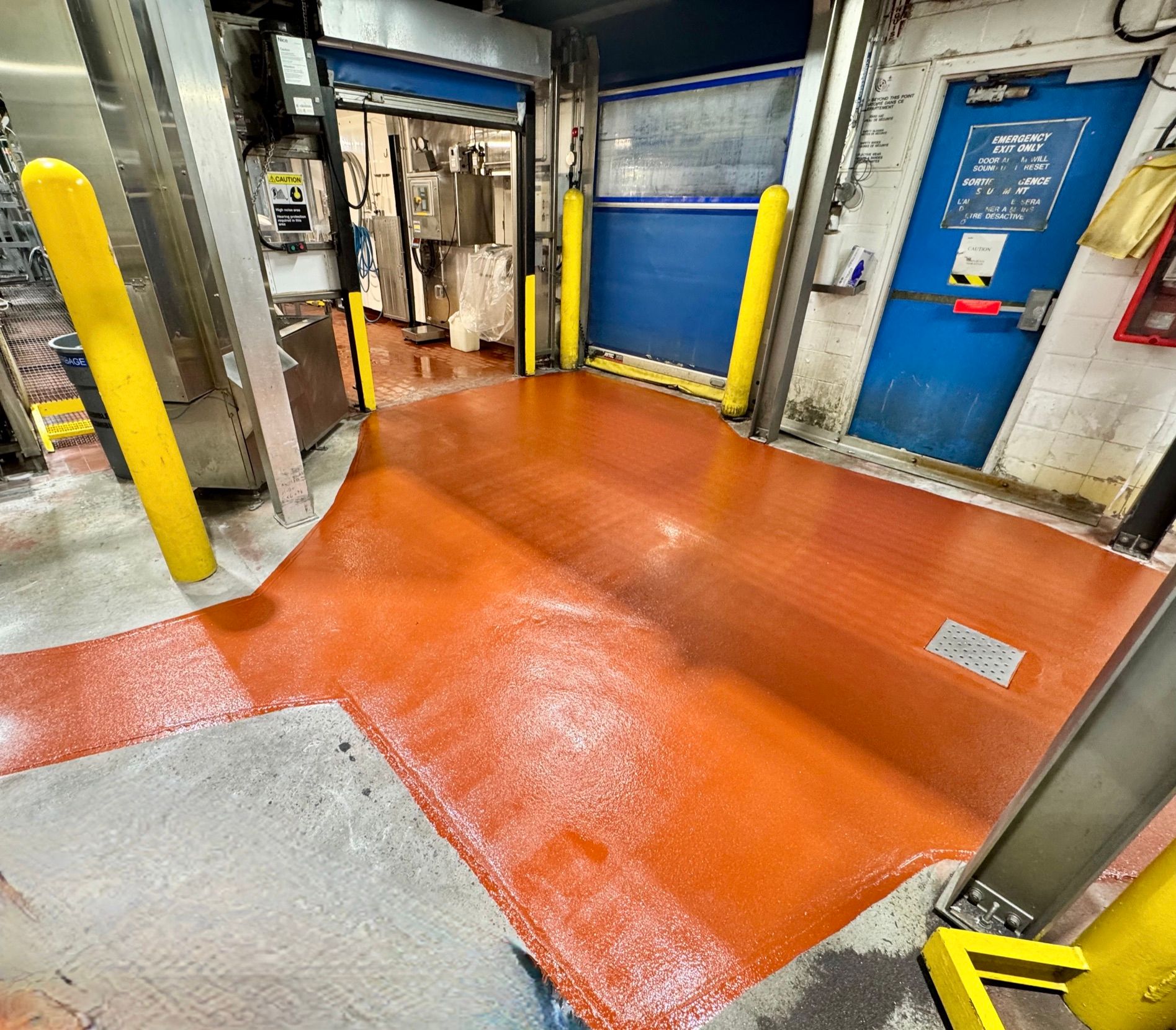 Food and beverage facility with freshly applied orange epoxy flooring and safety bollards