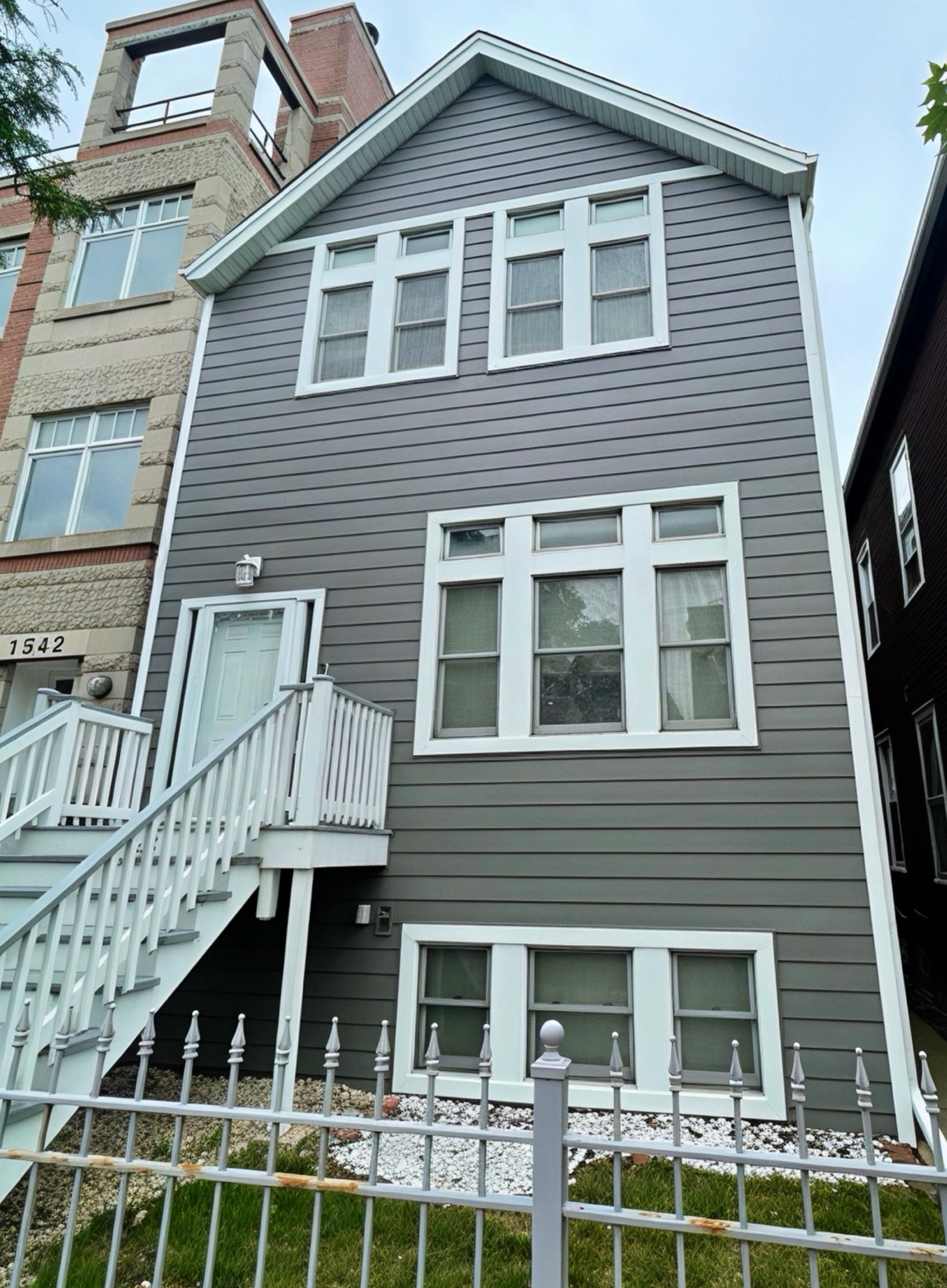 Completed siding replacement on a two-story home in the Chicago suburbs featuring ASCEND composite cladding in a warm gray tone
