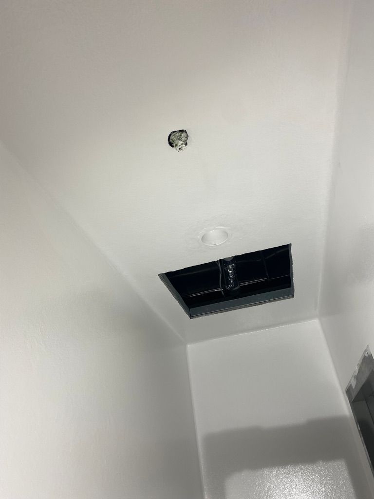 White seamless ceiling and wall finish in manufacturing facility showing penetration sealing detail