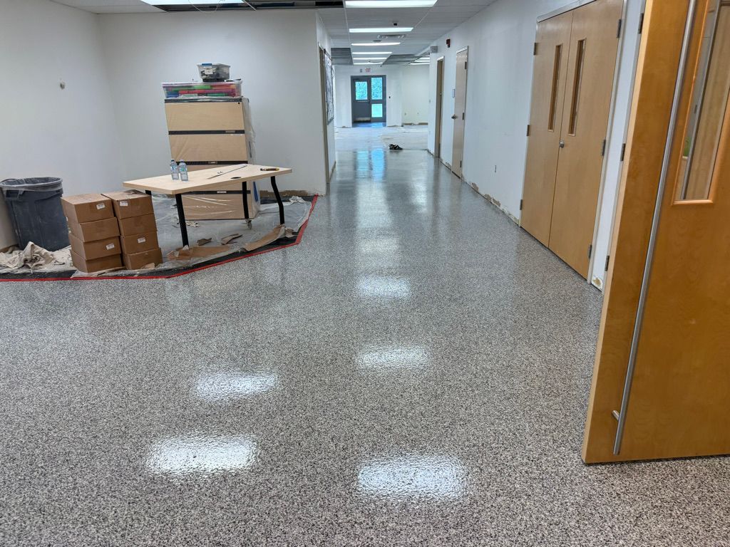 Polished school hallway with speckled gray epoxy floor, wooden classroom doors and recessed ceiling lighting