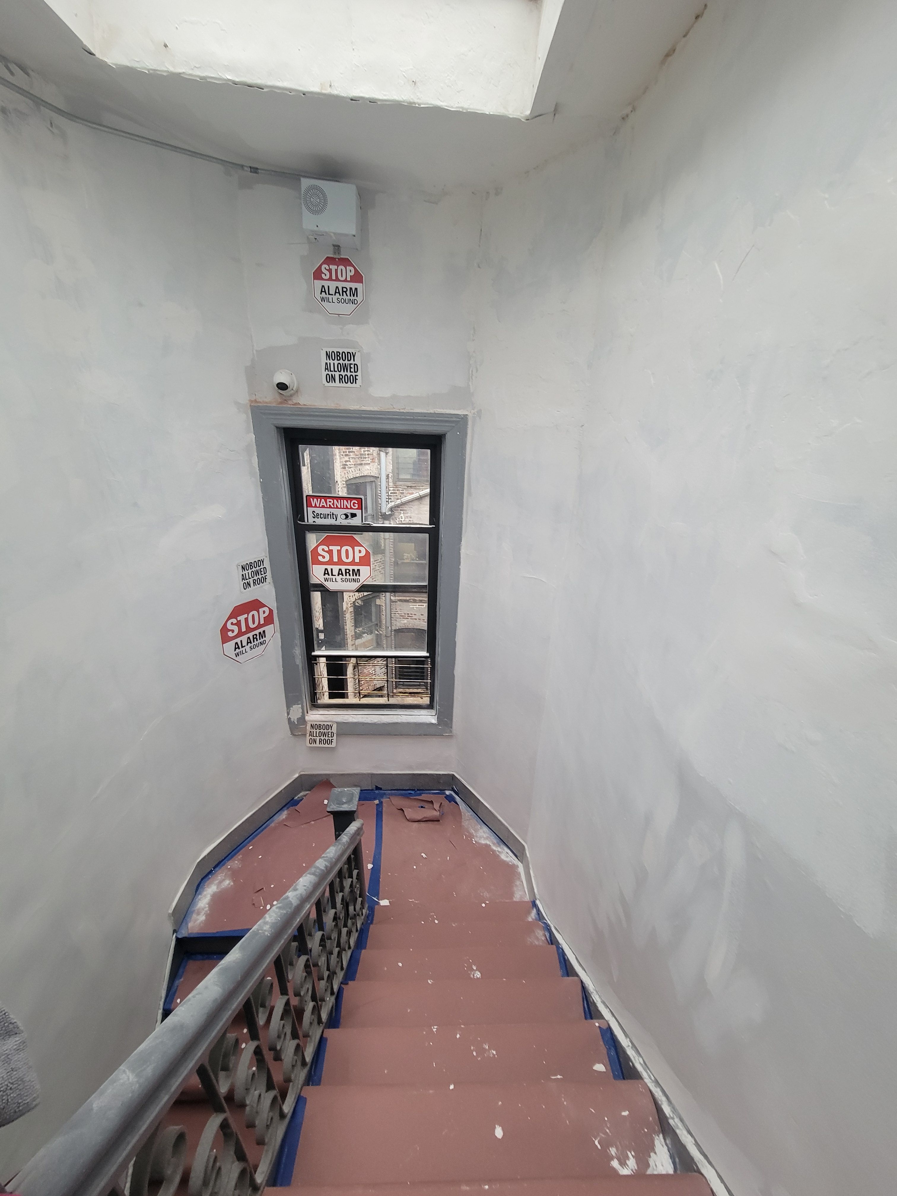 Roof landing repair - freshly painted white stairwell walls with warning signs