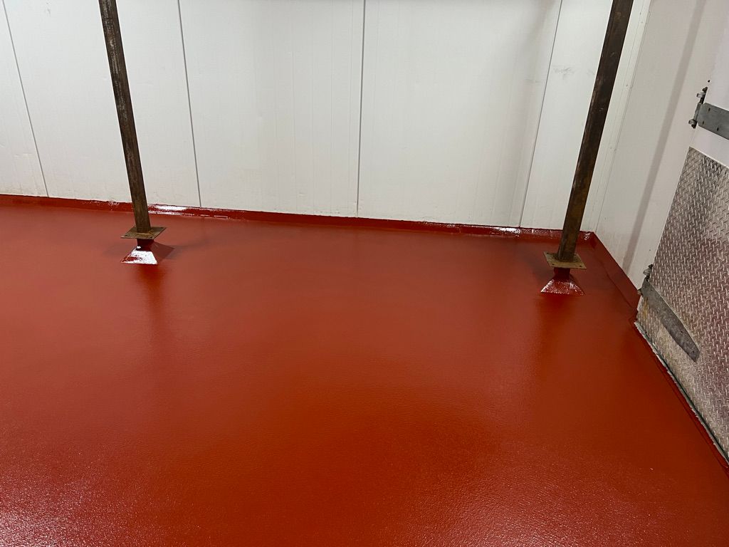 Corner of food and beverage facility with glossy red epoxy floor and safety bollards