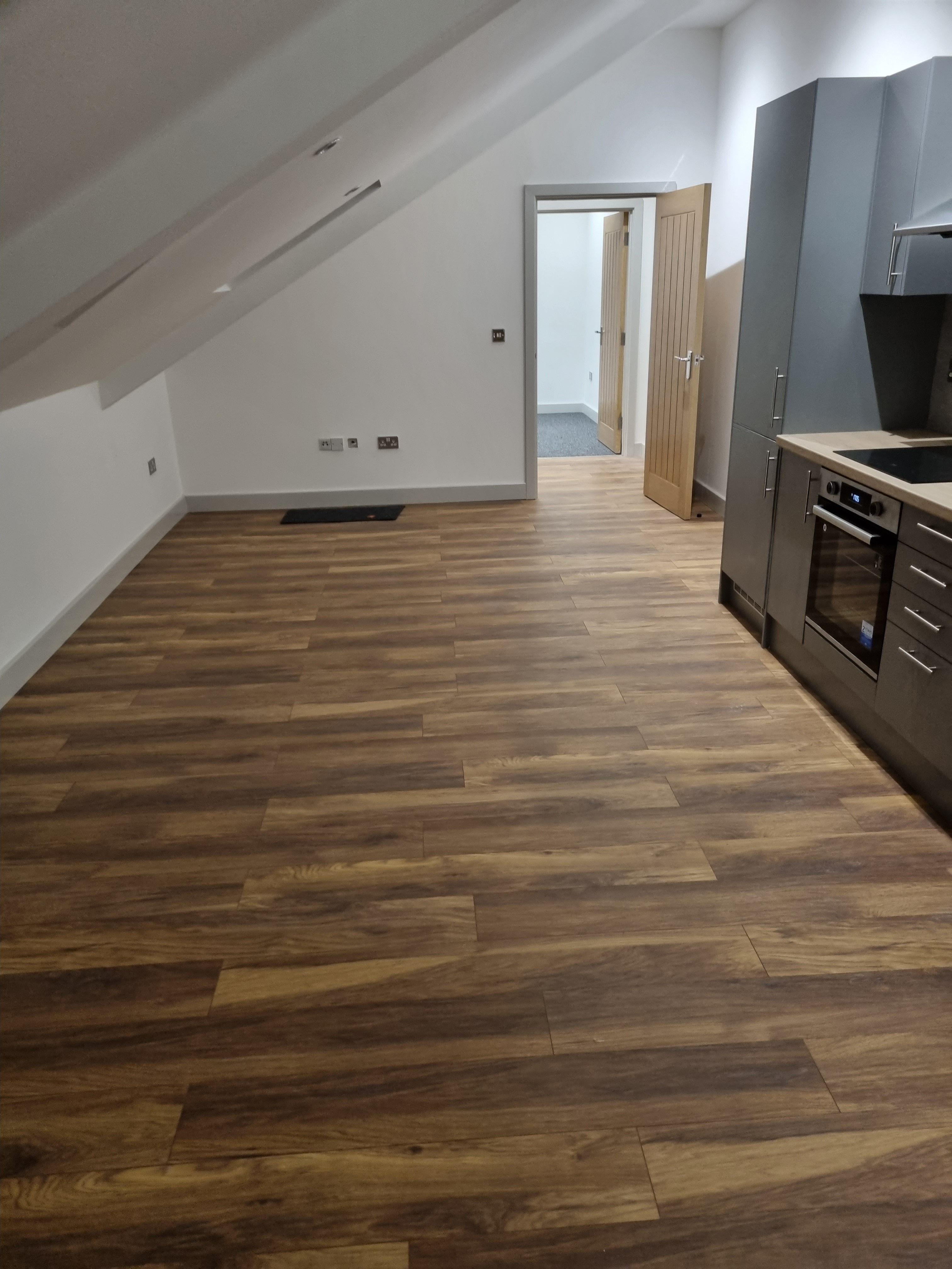 Modern kitchen with wood-effect vinyl flooring and grey cabinets