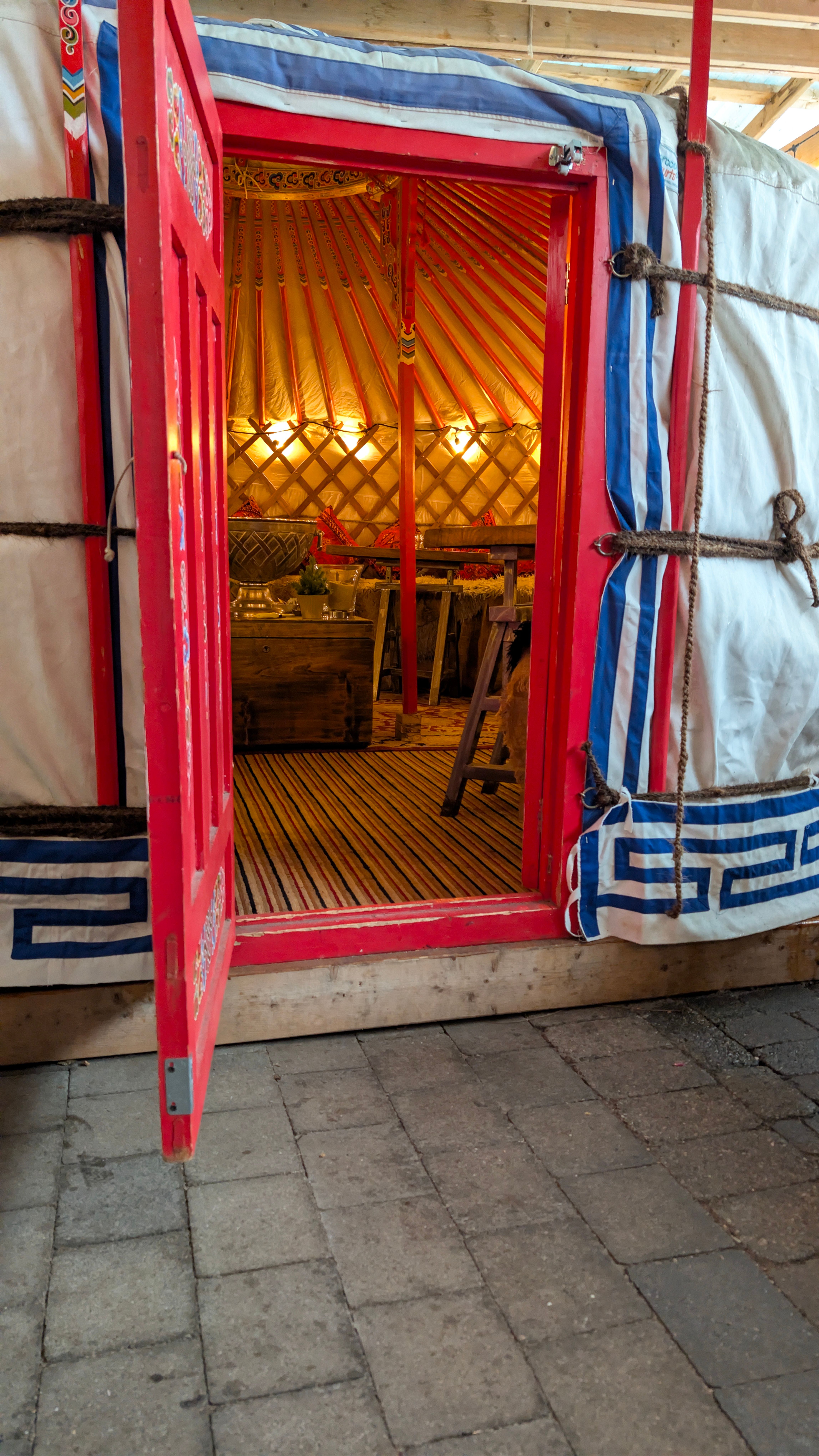 The open red door of Olio's Mongolian yurt, warm candlelight glowing inside