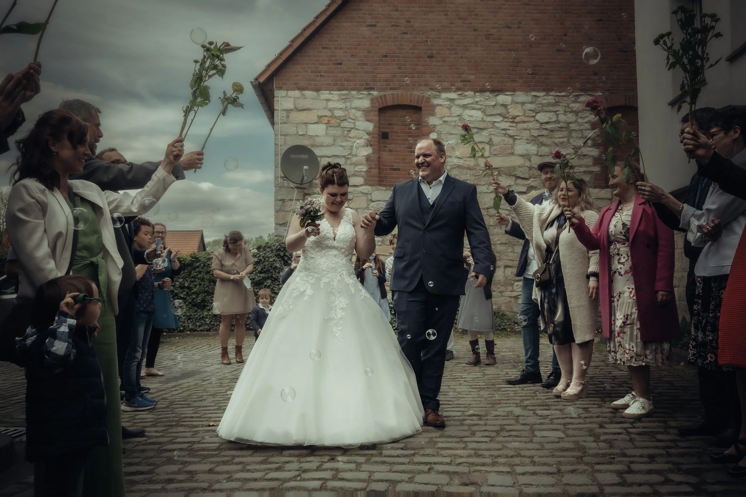 Bride and groom walking through flower arch, golden hour wedding portrait in Germany
