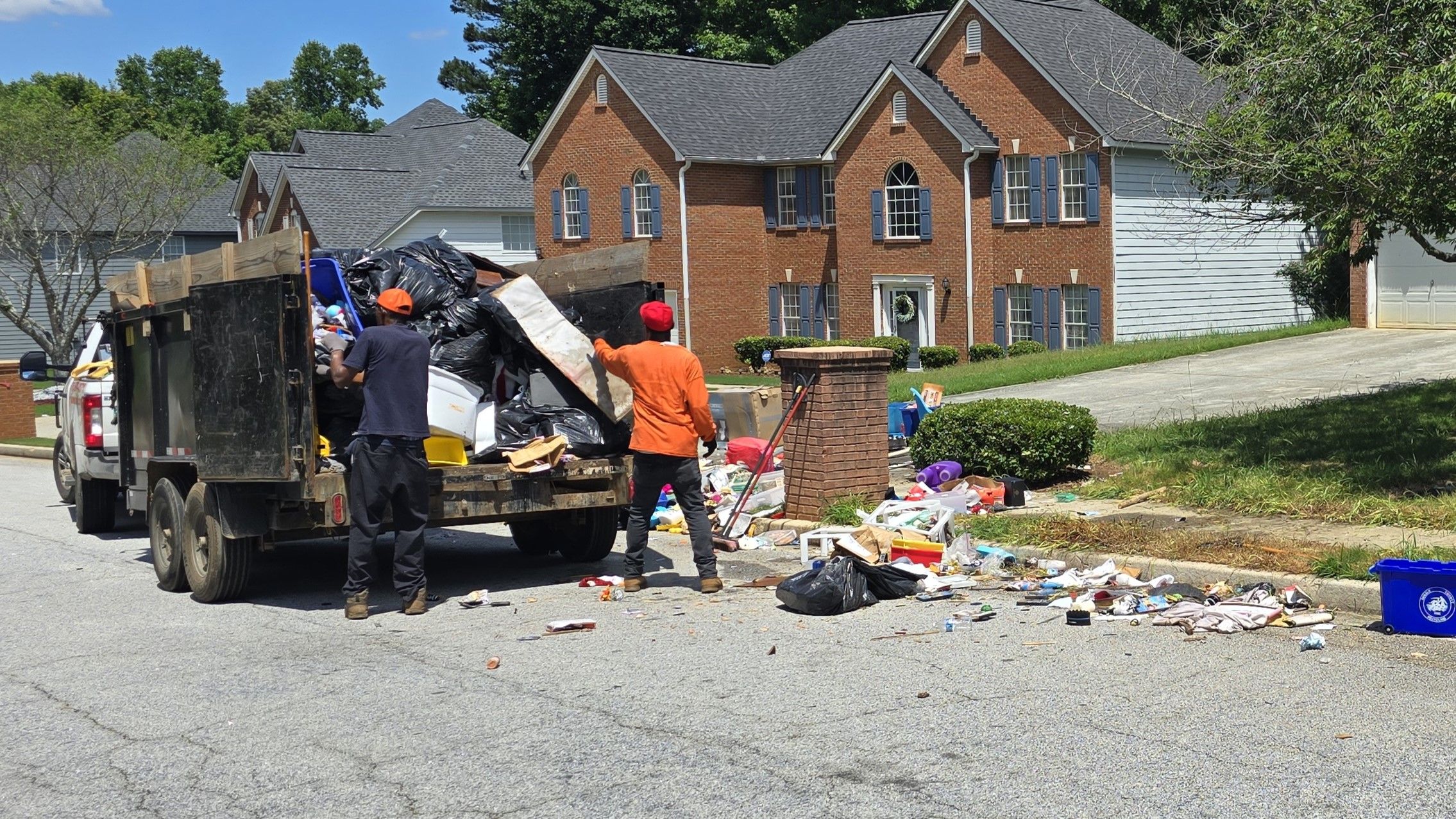 Team loading trailer at curbside job - GoGo Junk Removal technicians loading trash into black dump trailer