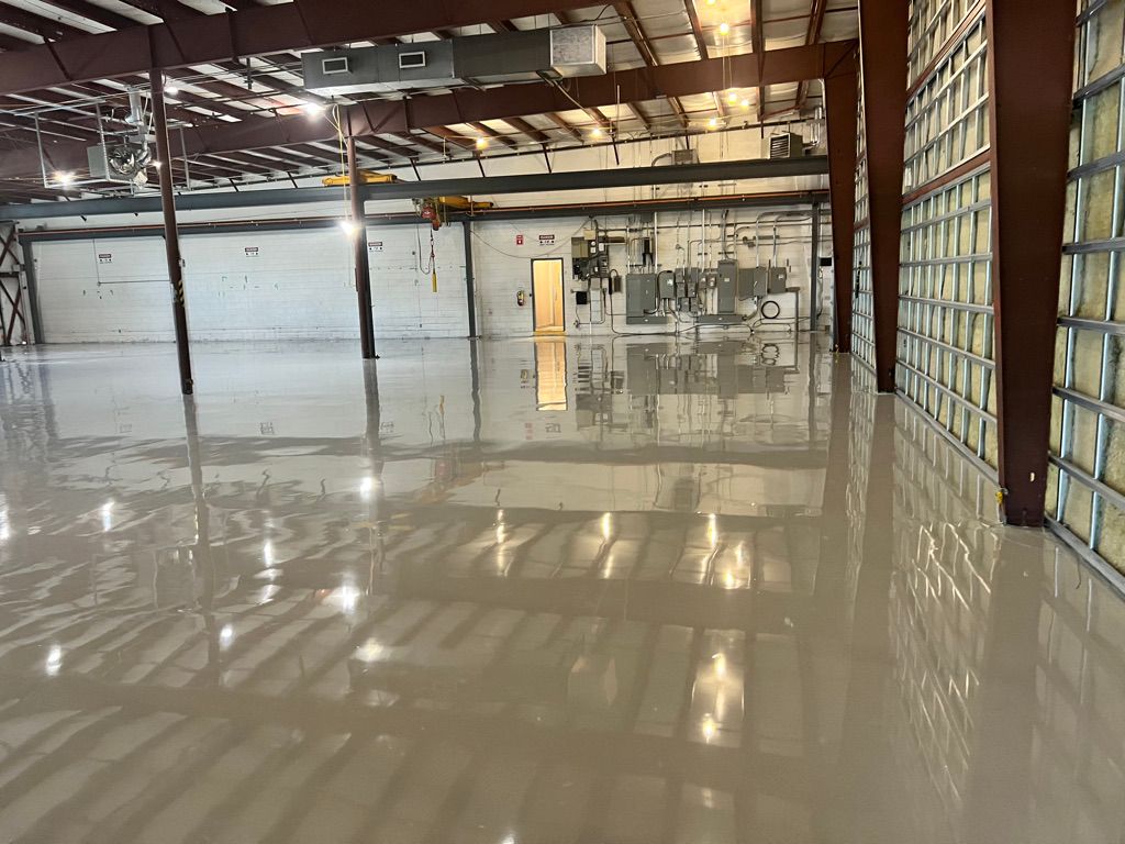 Large industrial warehouse with highly reflective smooth floor, support columns, garage doors and glass block wall section