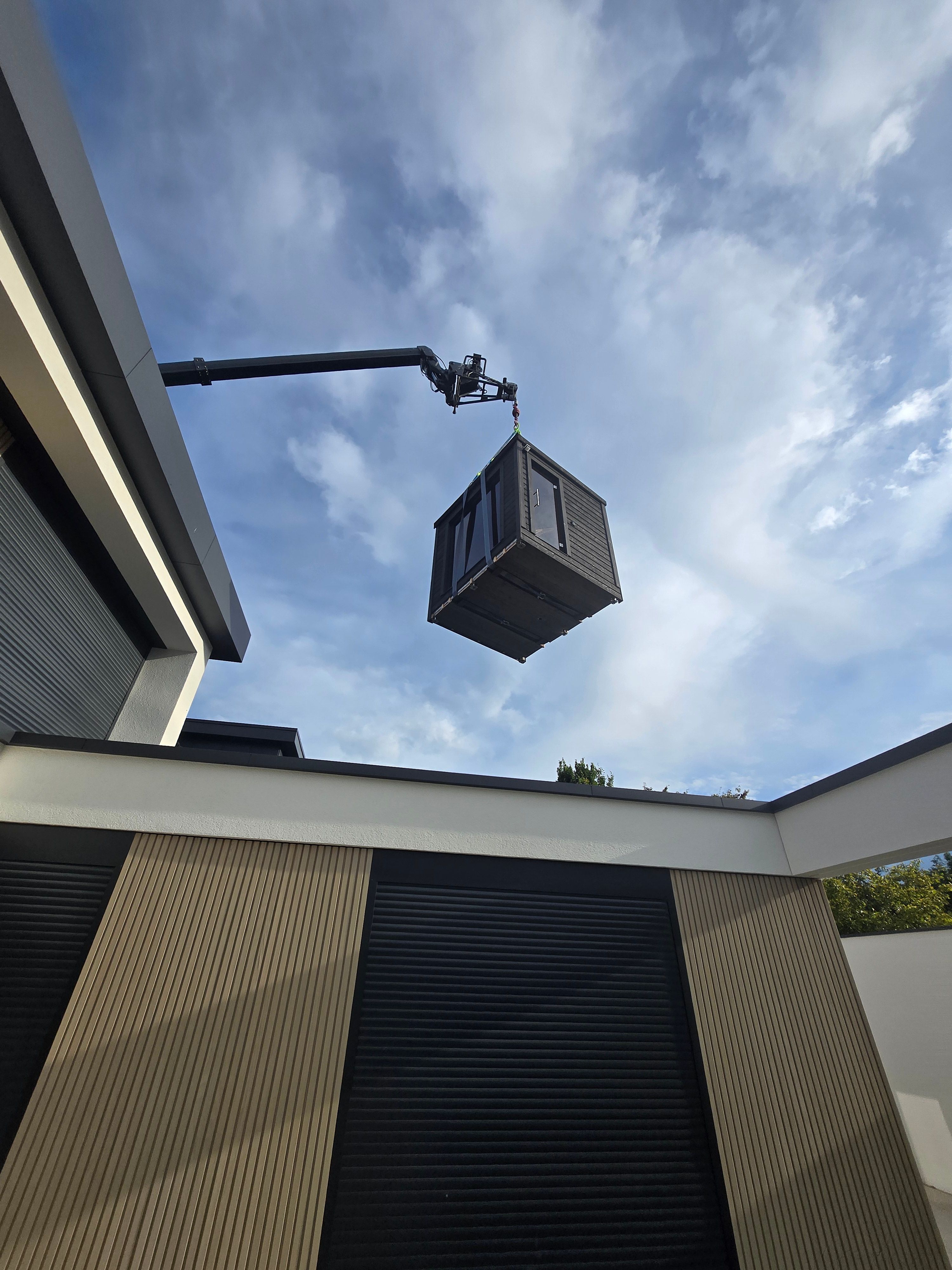 Crane lifting a cabin unit high above a building
