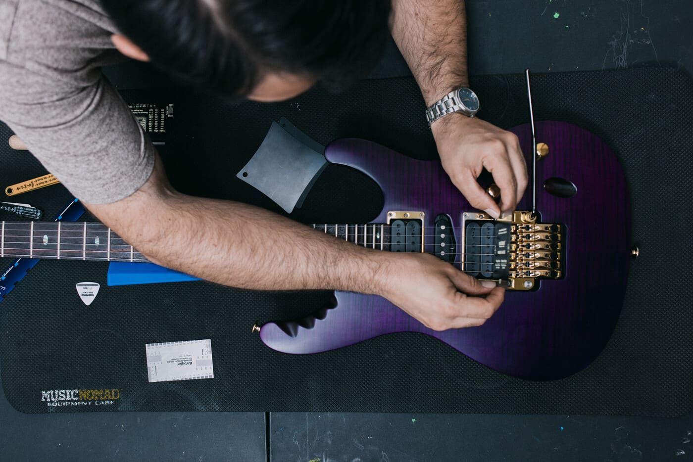 Tyler adjusting the bridge of a purple electric guitar on a professional work mat during an MPA