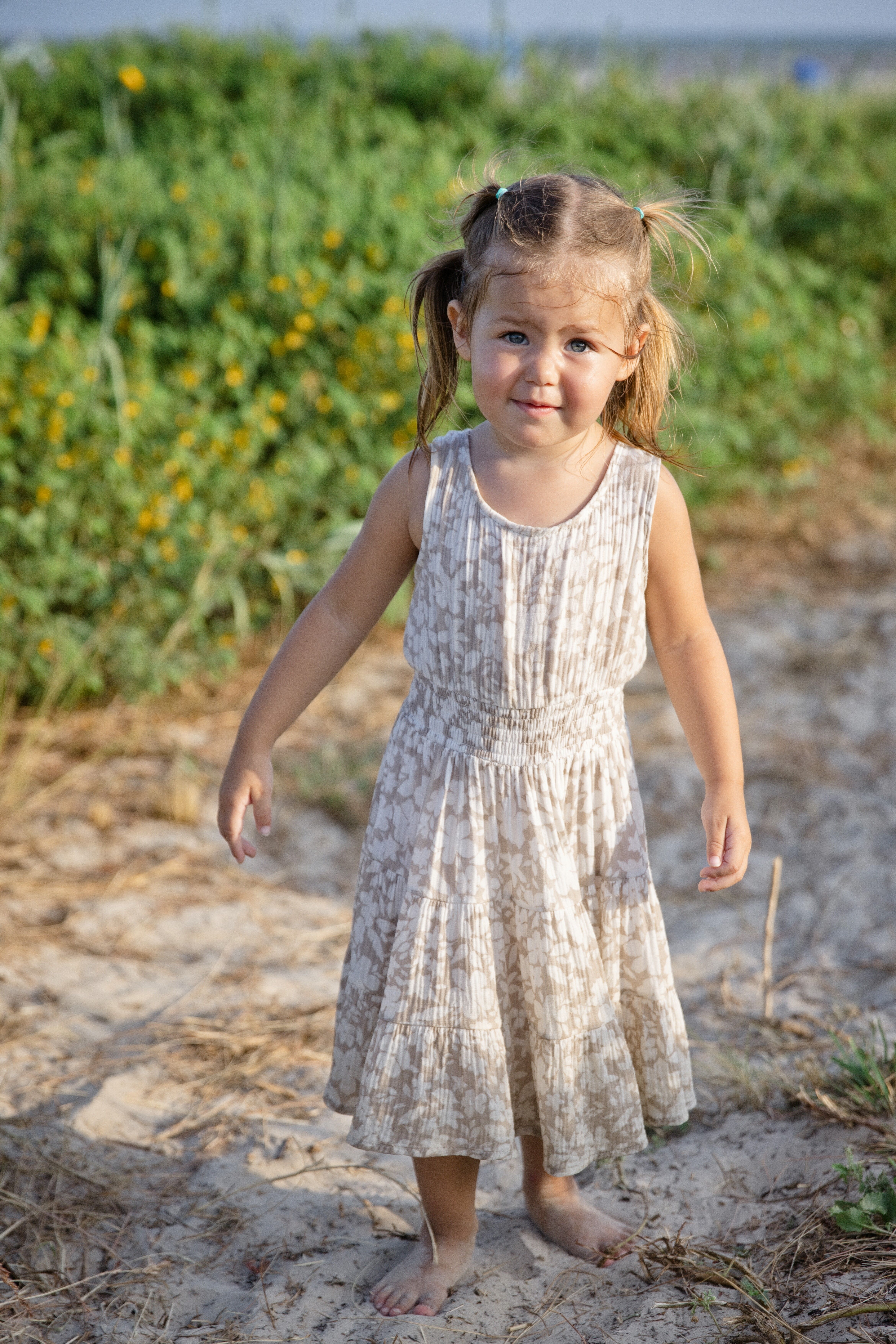 Little girl standing barefoot on a sandy path
