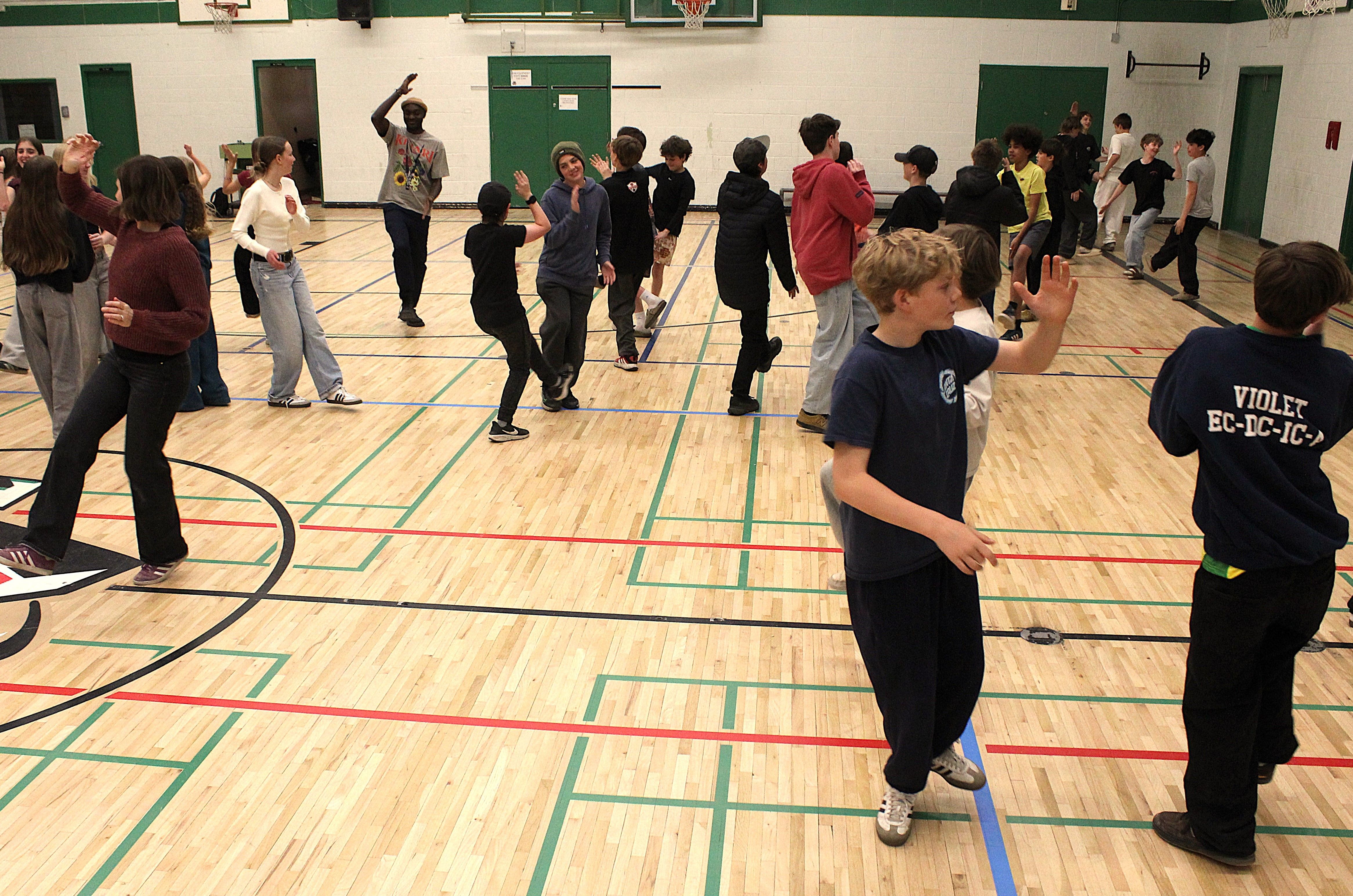 Students raising hands and interacting during a Groove Activation in a school gymnasium