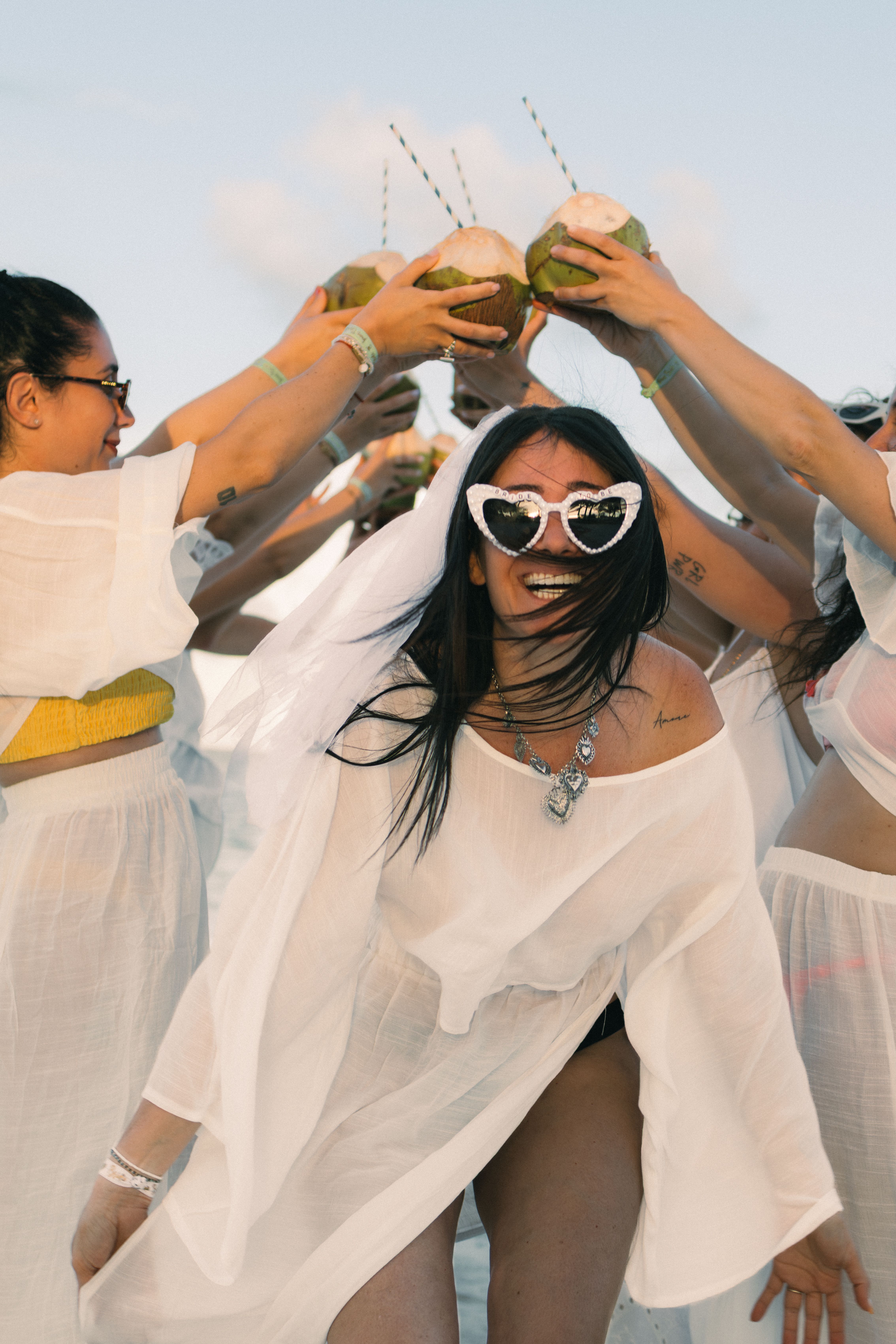Bachelorette party group celebrating with coconuts on beach