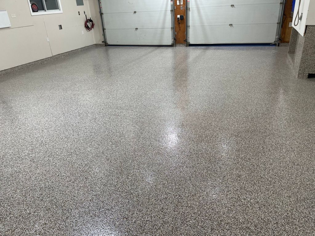 Residential garage with speckled gray epoxy floor and two white garage doors