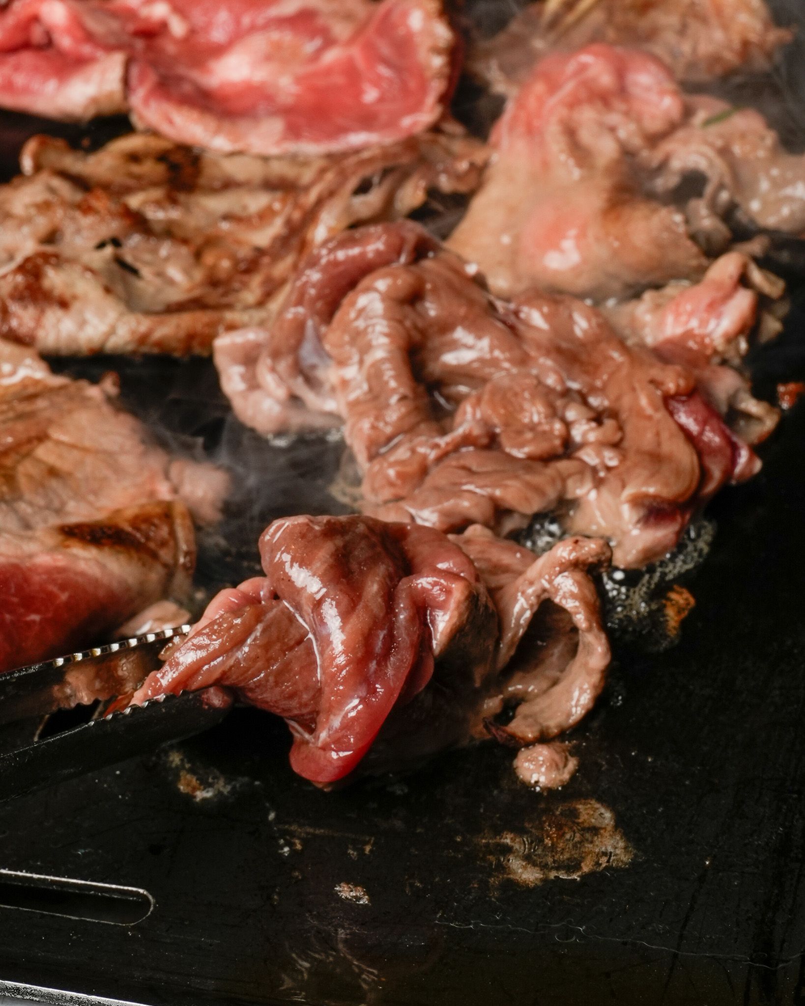 Thinly sliced meat cooking on the grill