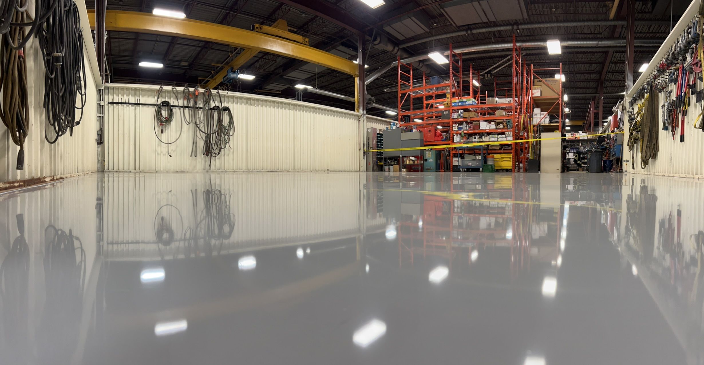 Industrial distribution facility with polished epoxy floor, coiled cable stations, orange shelving and overhead crane