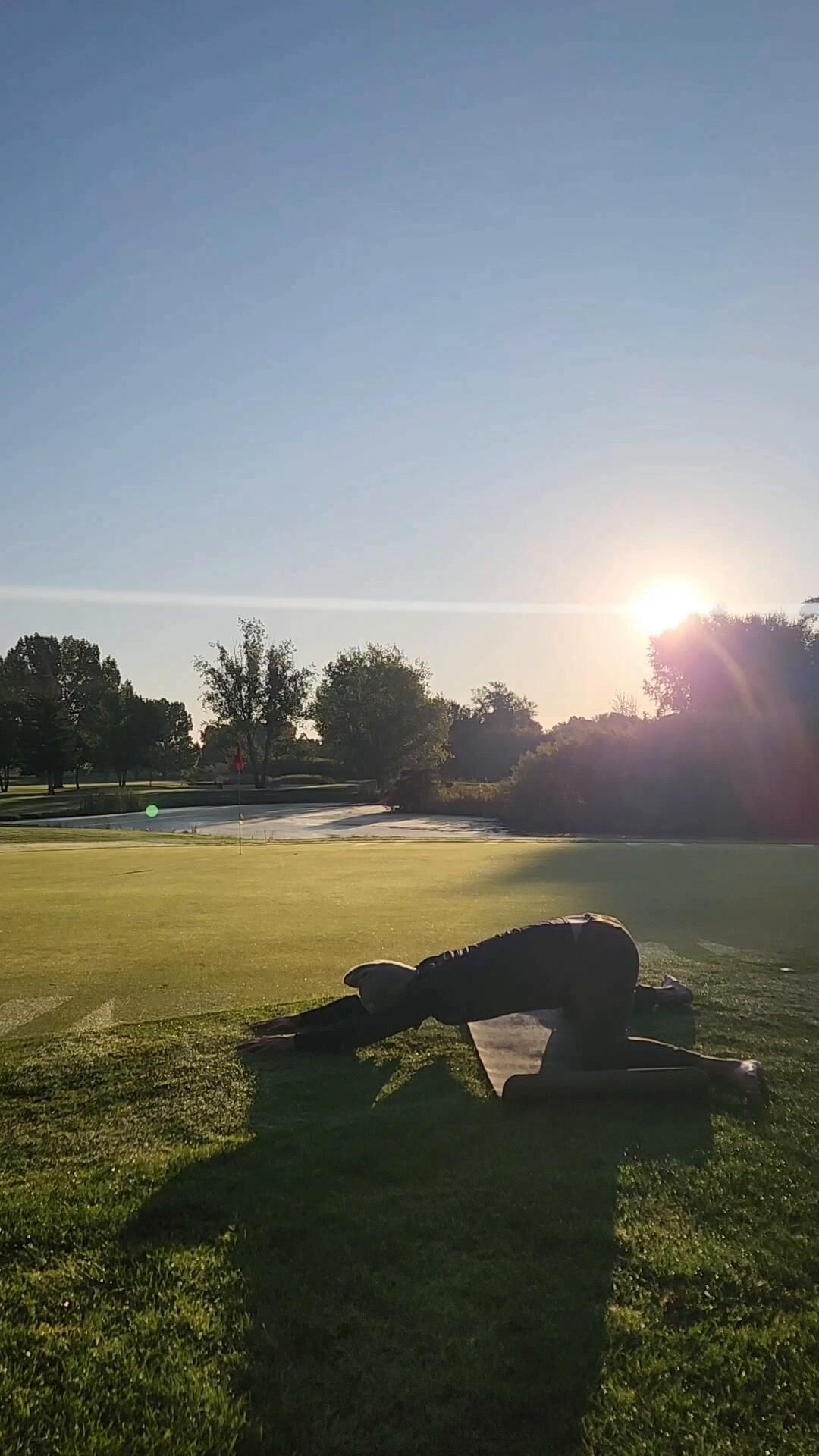 Child's pose on golf course at sunset