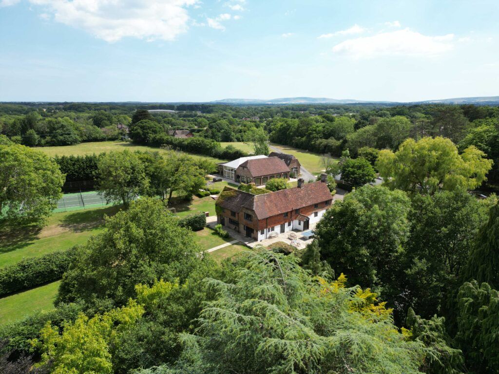 Aerial drone view of rural property with tennis court and gardens in East Sussex
