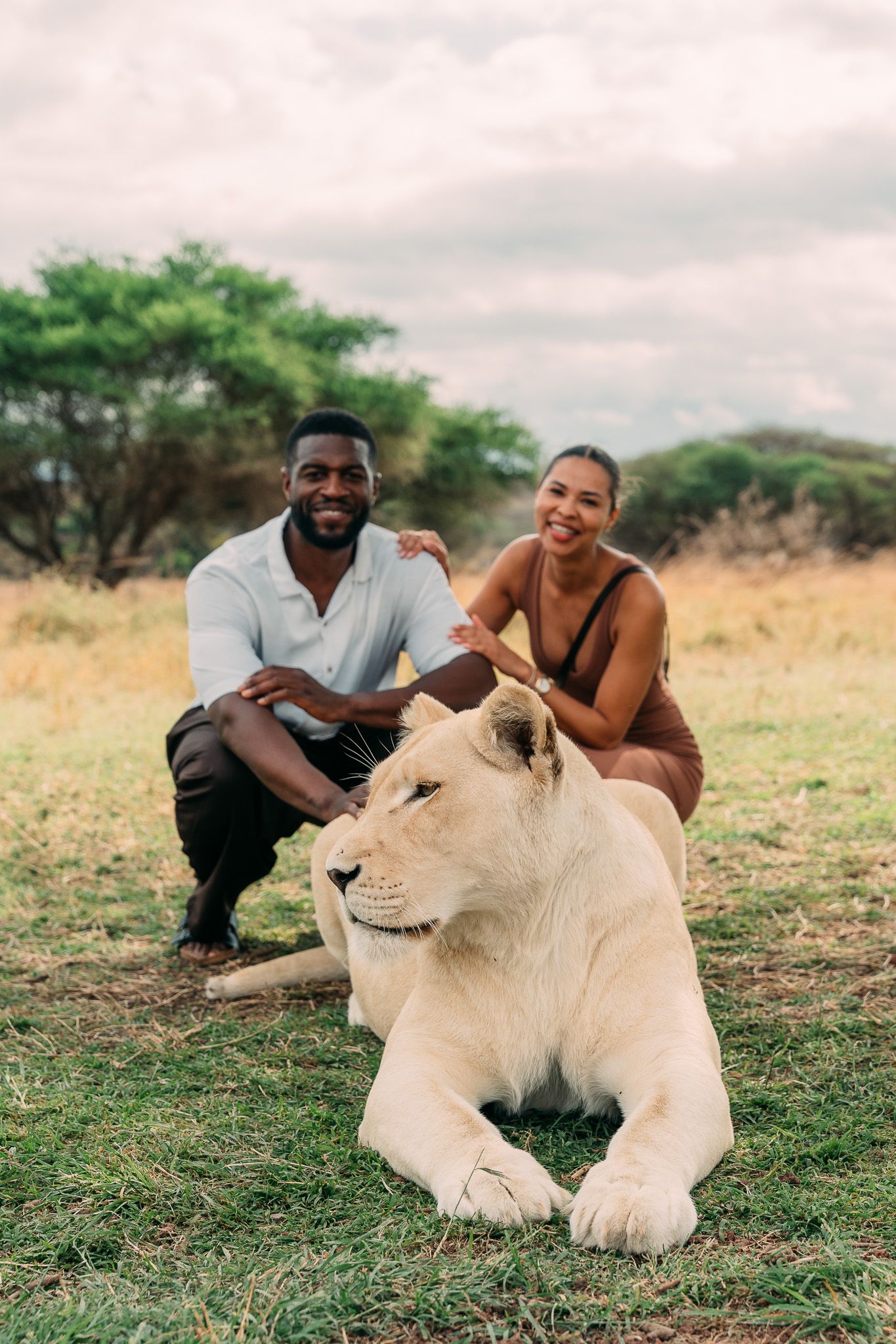 Couple crouching behind lioness at Serval Wildlife Park — lion walk experience Zanzibar
