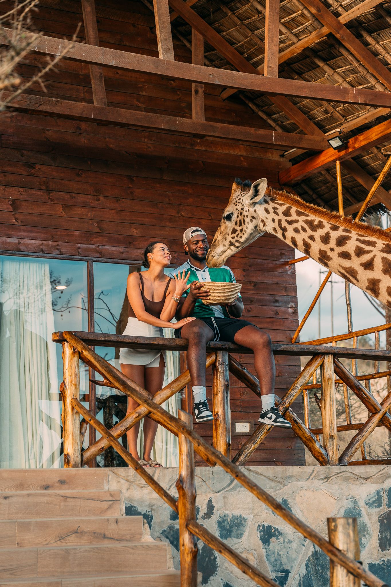 Couple feeding giraffe from wooden balcony at Serval Wildlife Park — unique engagement photography