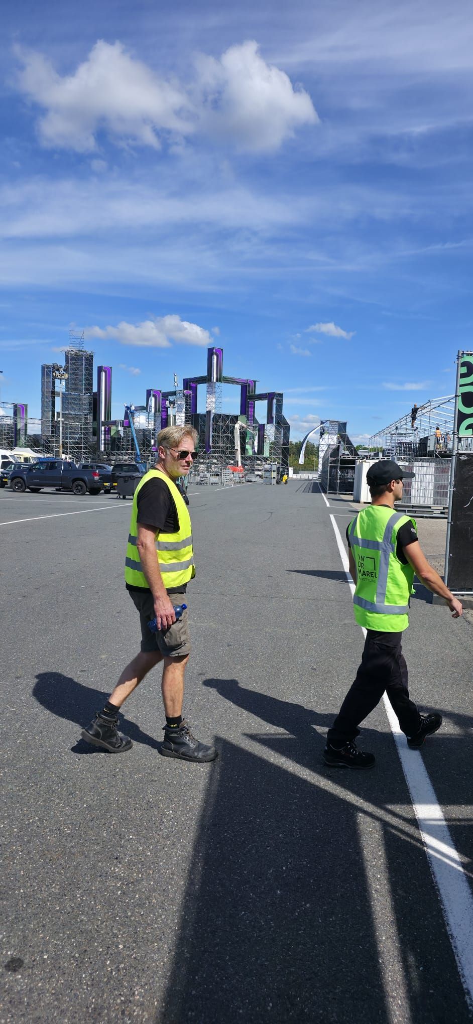 Overzicht van een festivalterrein in opbouw met tenten, hekken en crewleden die samenwerken
