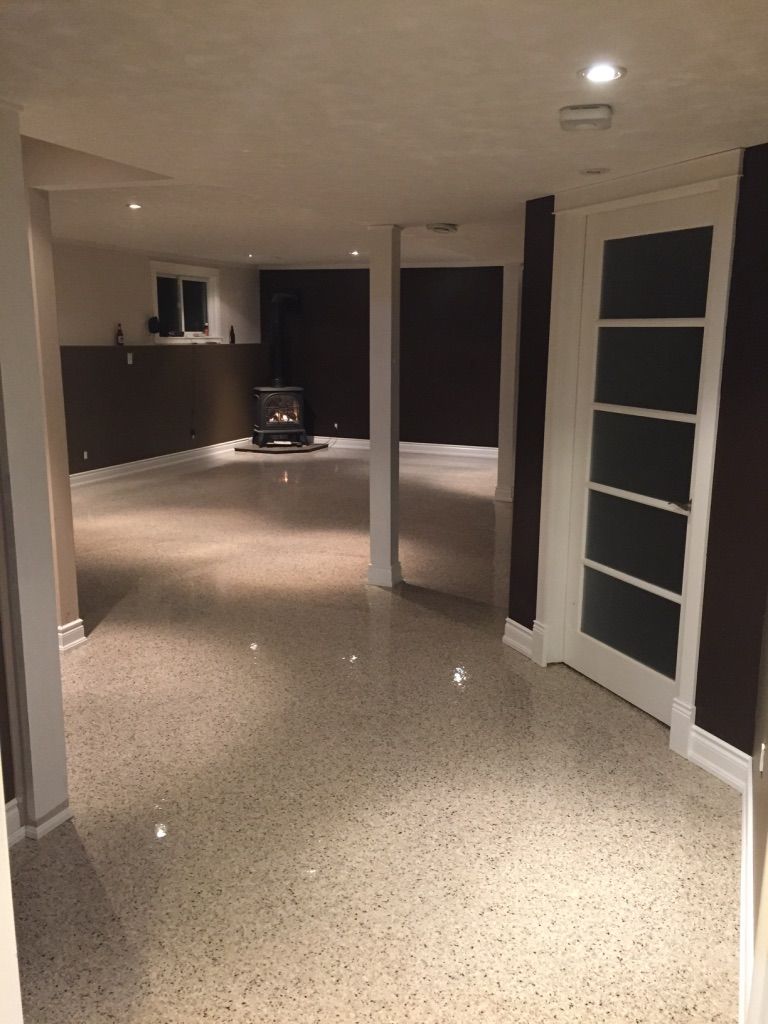Residential basement with beige speckle epoxy floor and gas fireplace